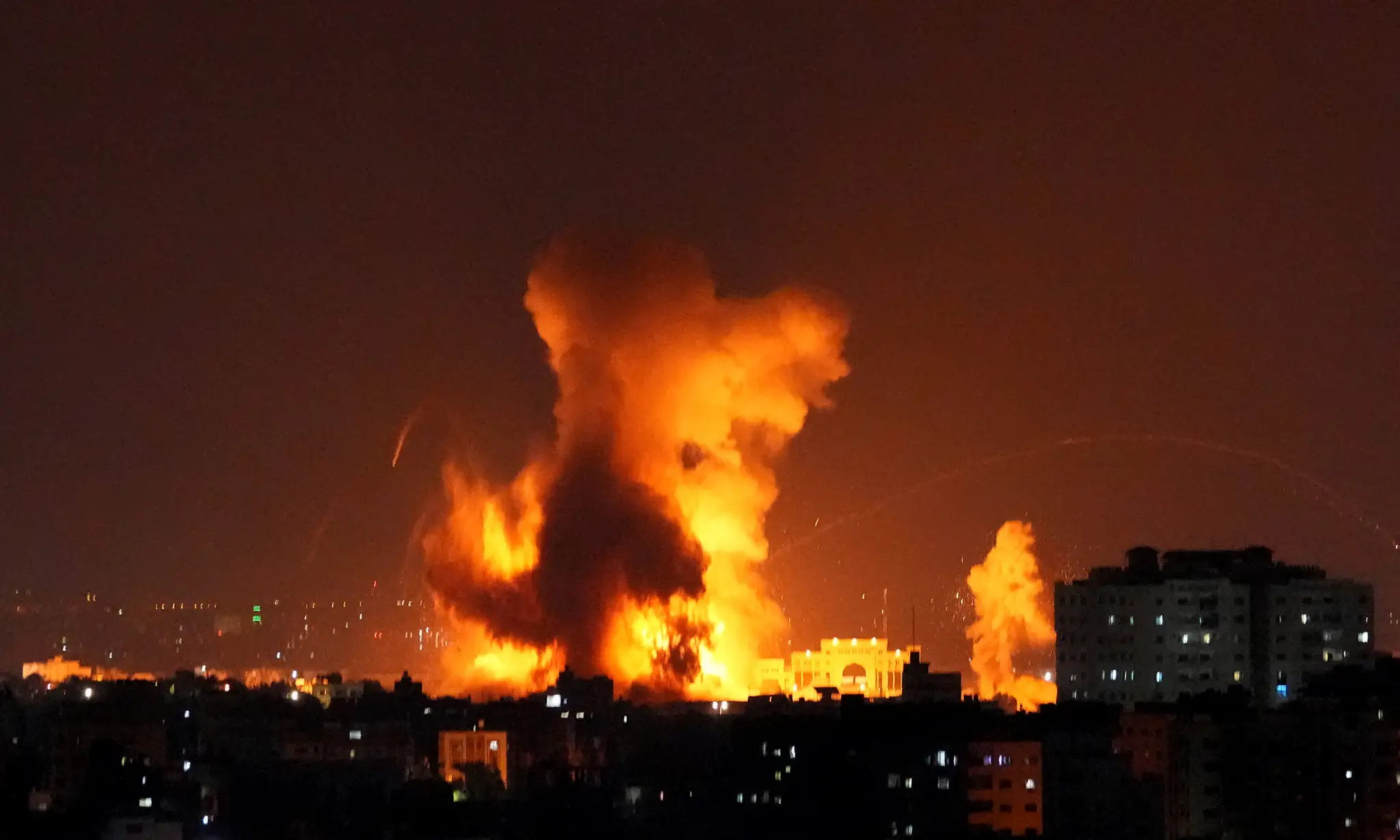 Na snímke dym a plamene stúpajú z budovy zasiahnutej raketami vystrelenými palestínskymi militantmi na Izrael.