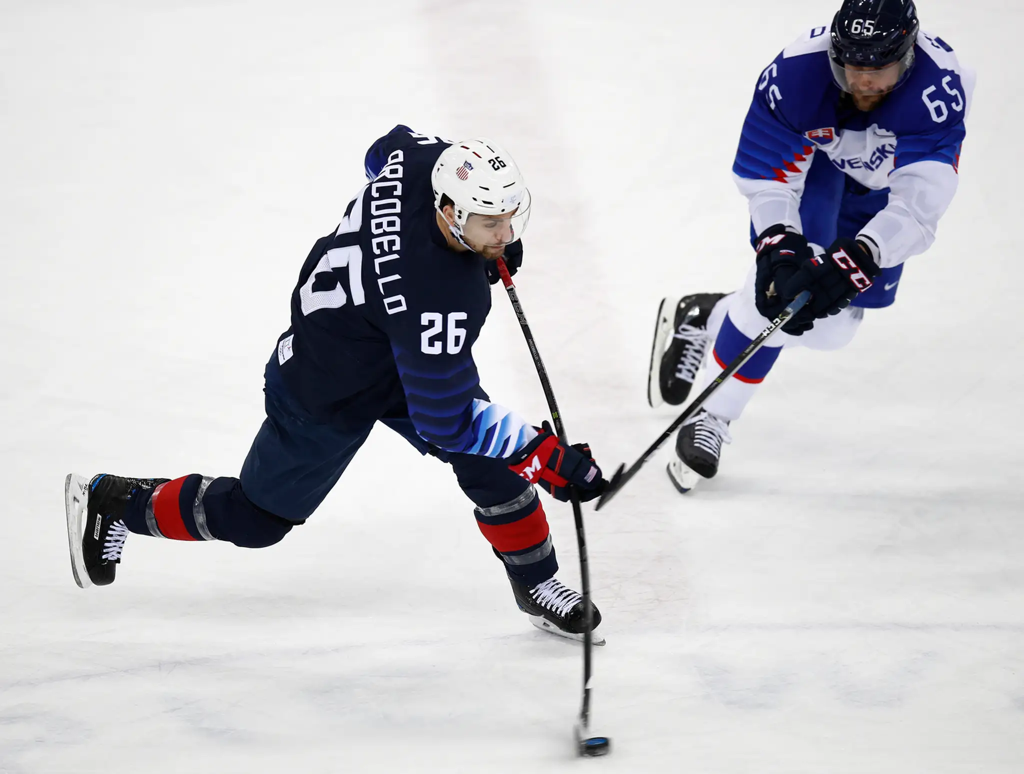 Američan Mark Arcobello (vľavo) páli na slovenskú bránku v osemfinále ZOH 2018, prizerá sa Tomáš Marcinko.