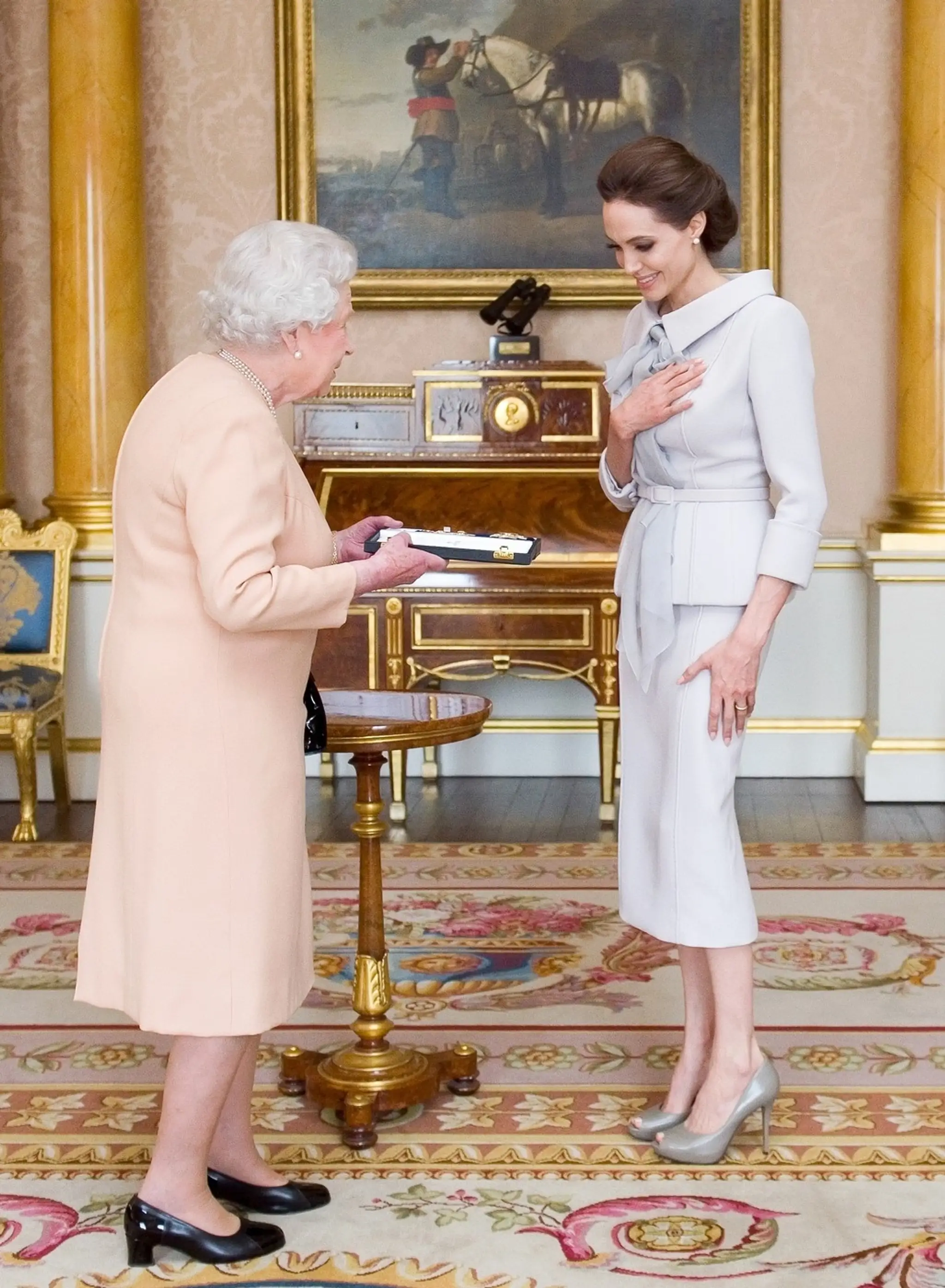 Kráľovná Alžbeta II. odovzdáva Angeline Jolie titul.