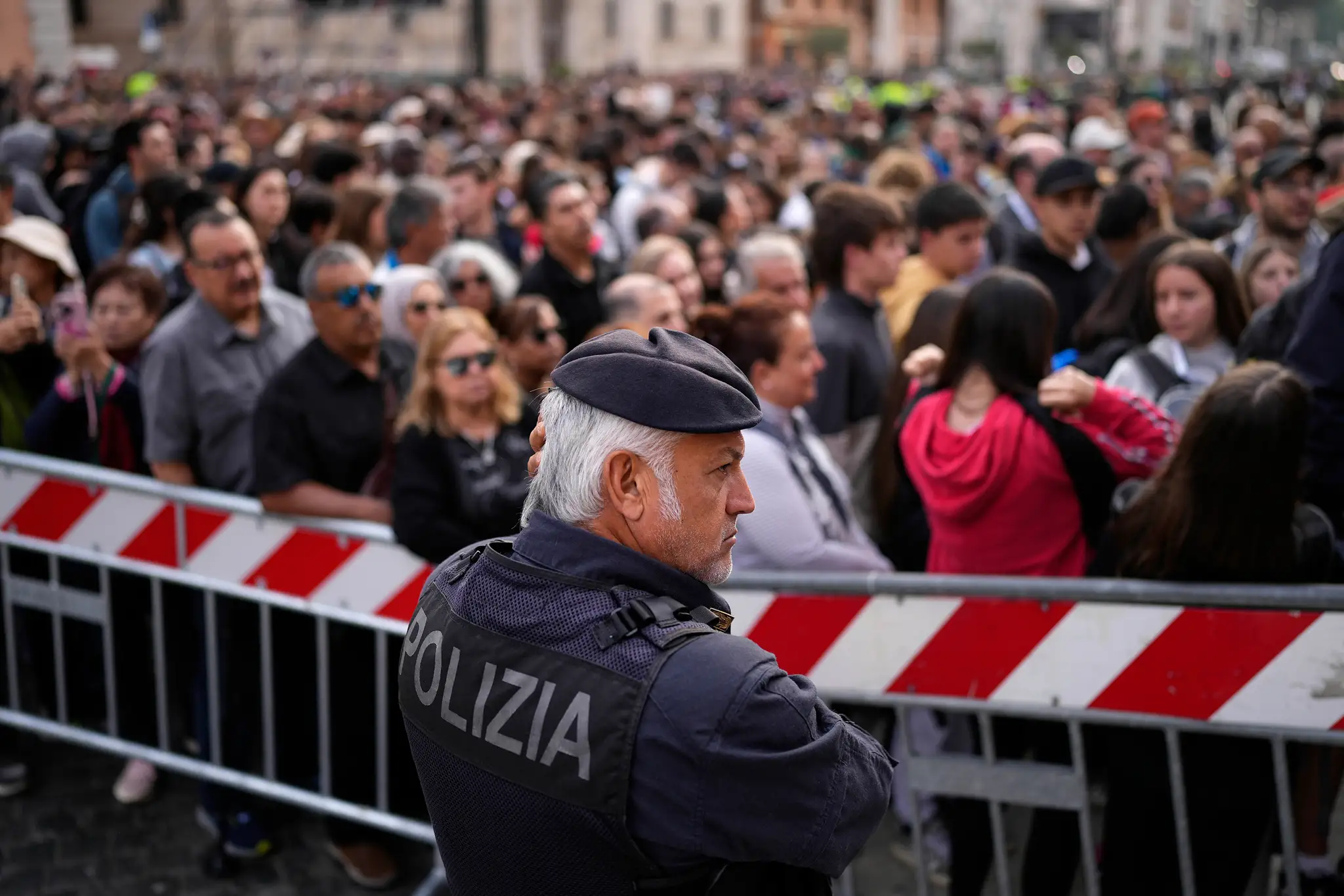 Policajt stojí vedľa ľudí, ktorí čakajú na vstup na Námestie svätého Petra, aby vzdali úctu zosnulému pápežovi Františkovi.