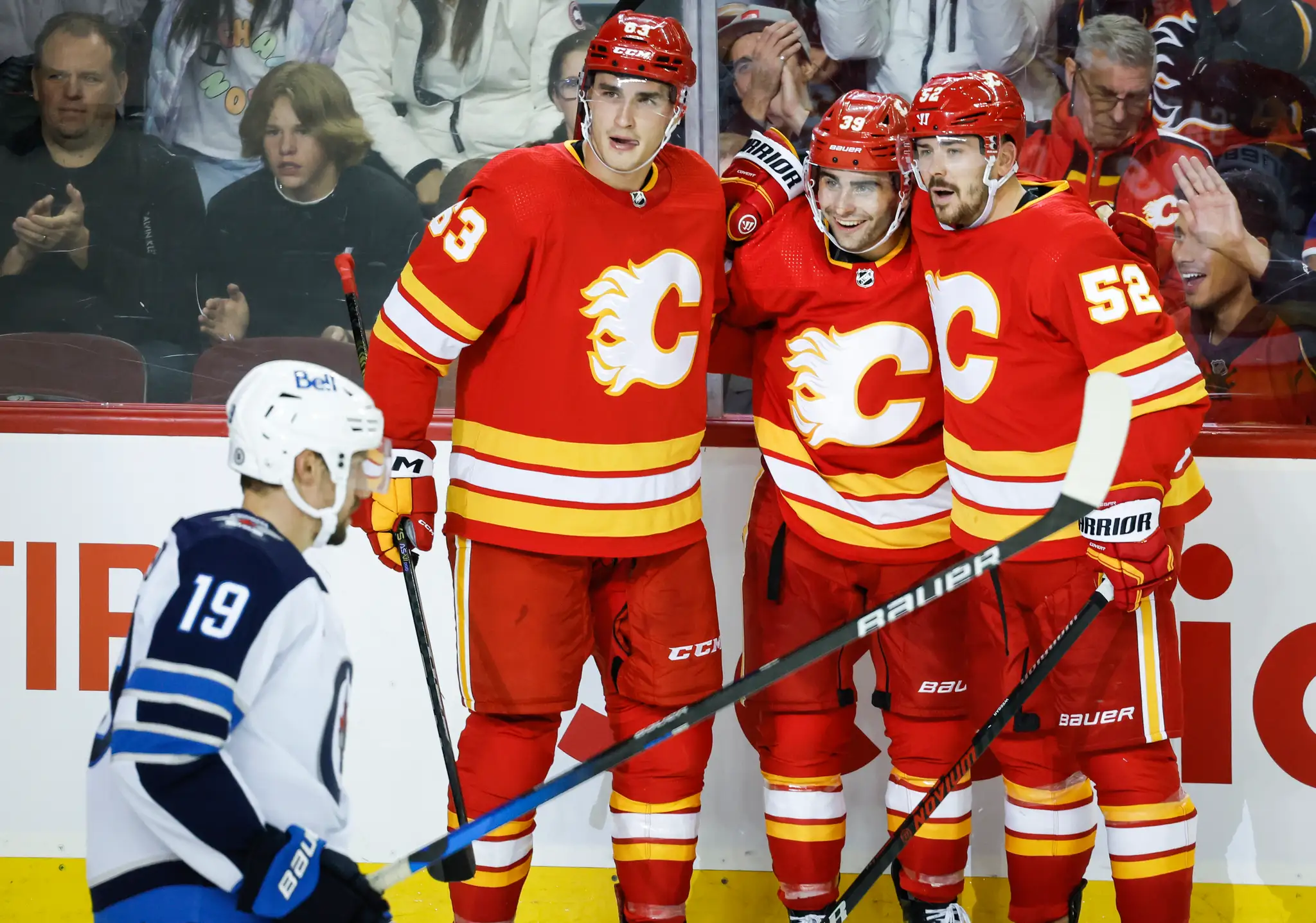 Hokejista Calgary Flames Matthew Coronato (39) sa teší z gólu so spoluhráčomi Adamom Ružičkom (63).