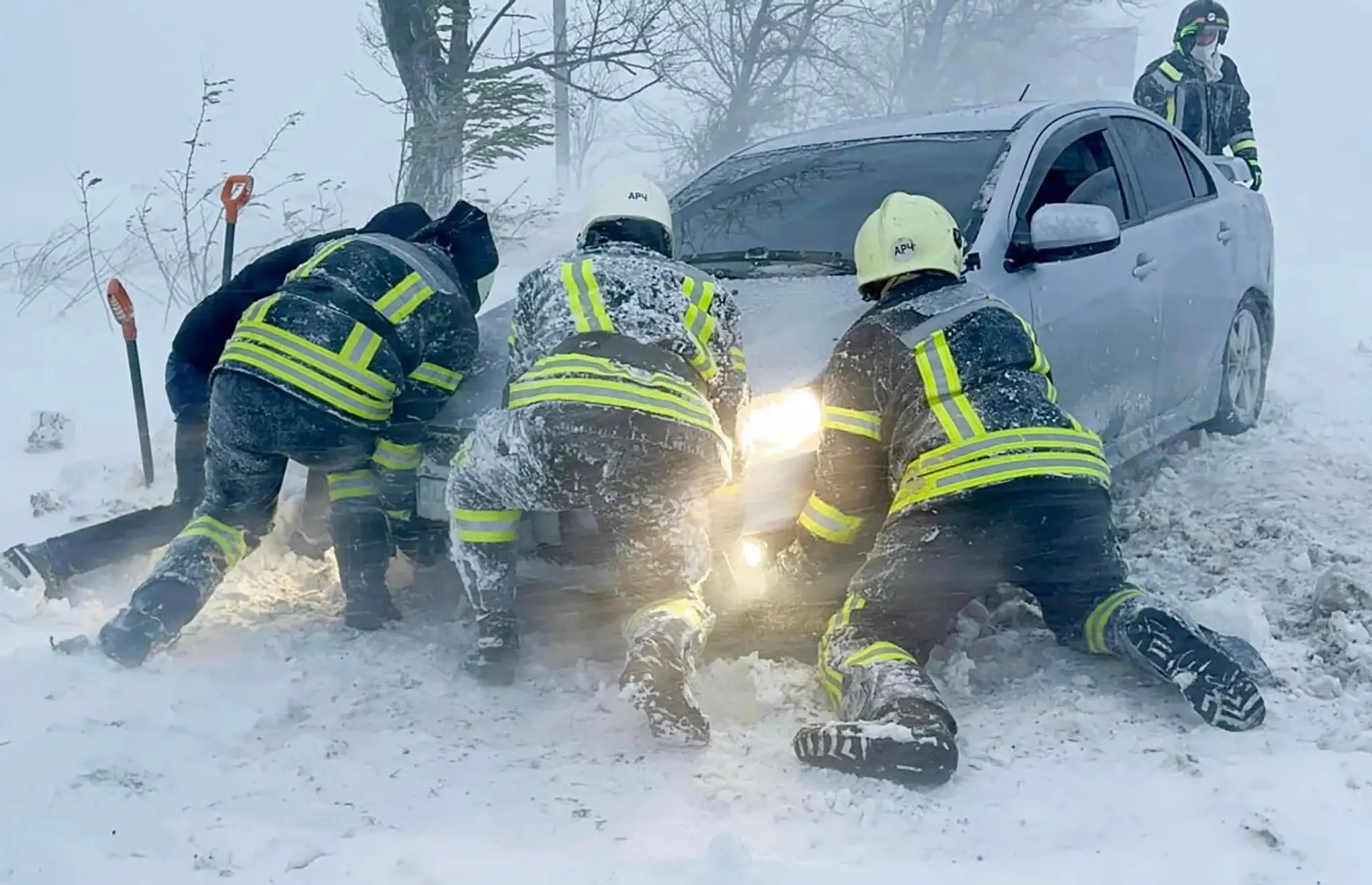 Ukrajinskí záchranári snažia odtlačiť auto, ktoré uviazlo na ceste počas snehovej víchrice v Odeskej oblasti.