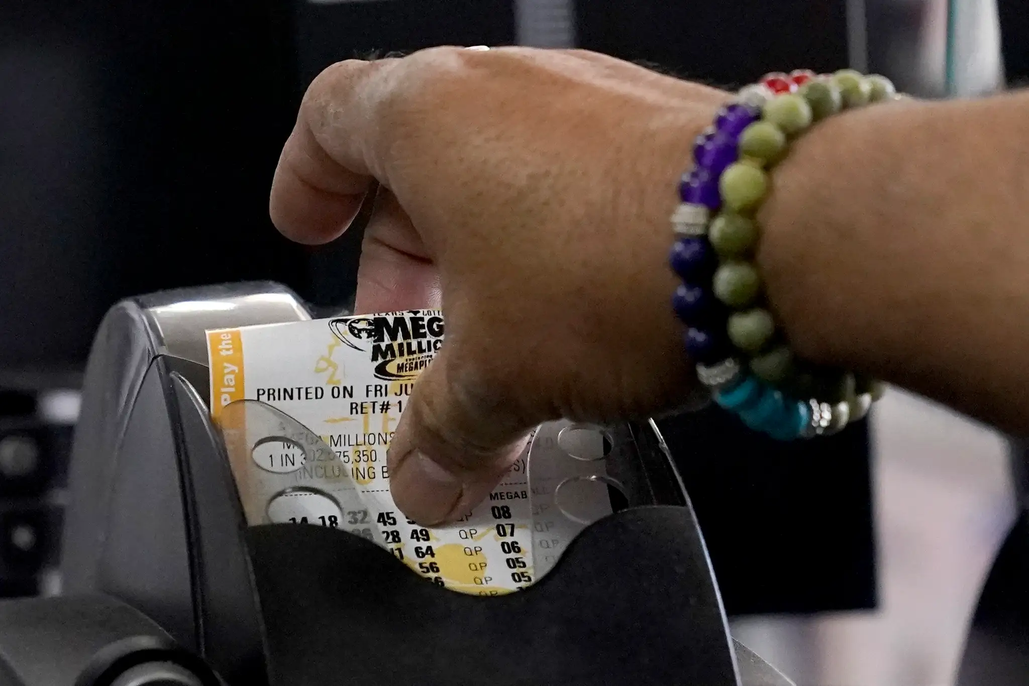 Zamestnanec samoobsluhy vyťahuje zákazníkovi tiket americkej lotérie Mega Millions v texaskom Richardsone.