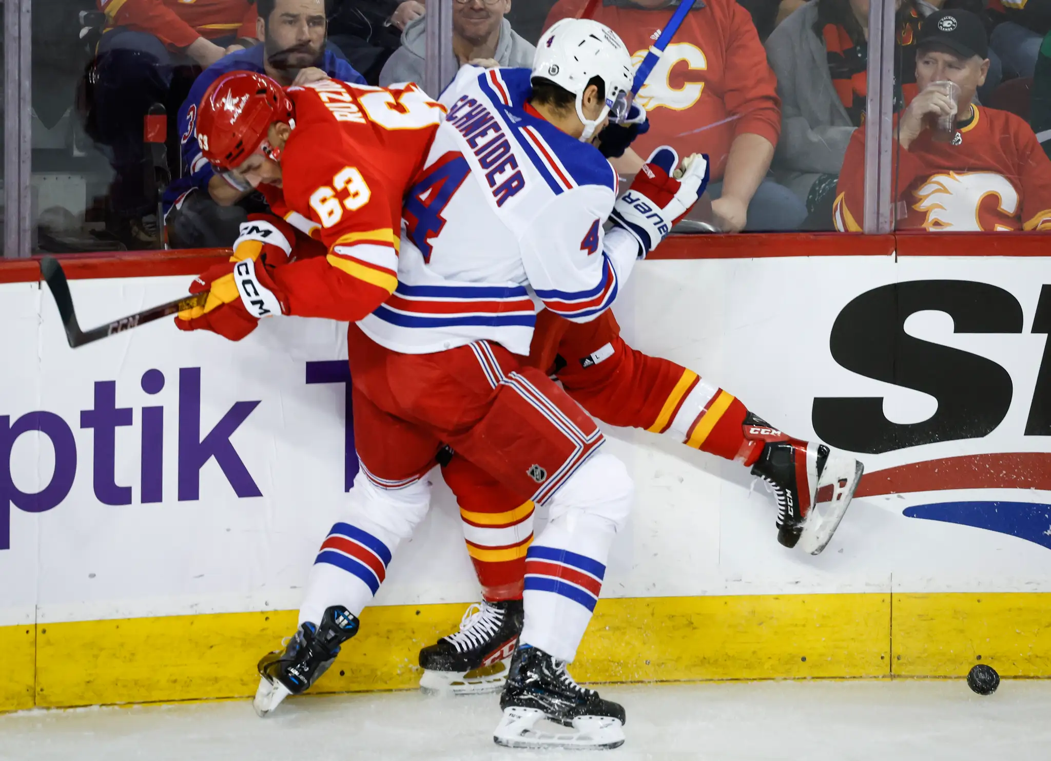 Na snímke zľava slovenský útočník Calgary Adam Ružička a obranca Rangers Braden Schneider.