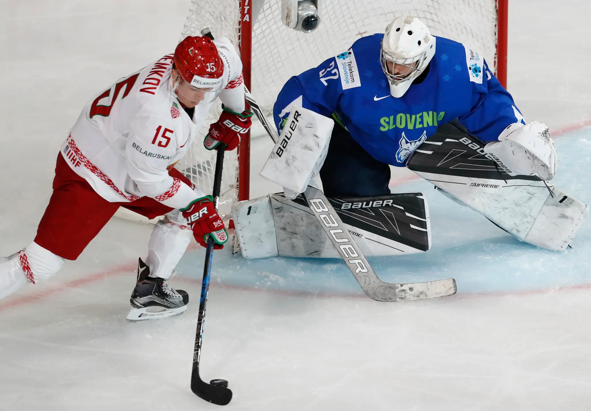 Bielorus Arťom Demkov (vľavo) útočí na slovinského brankára Kaspera Groselja v zápase MS 2017.