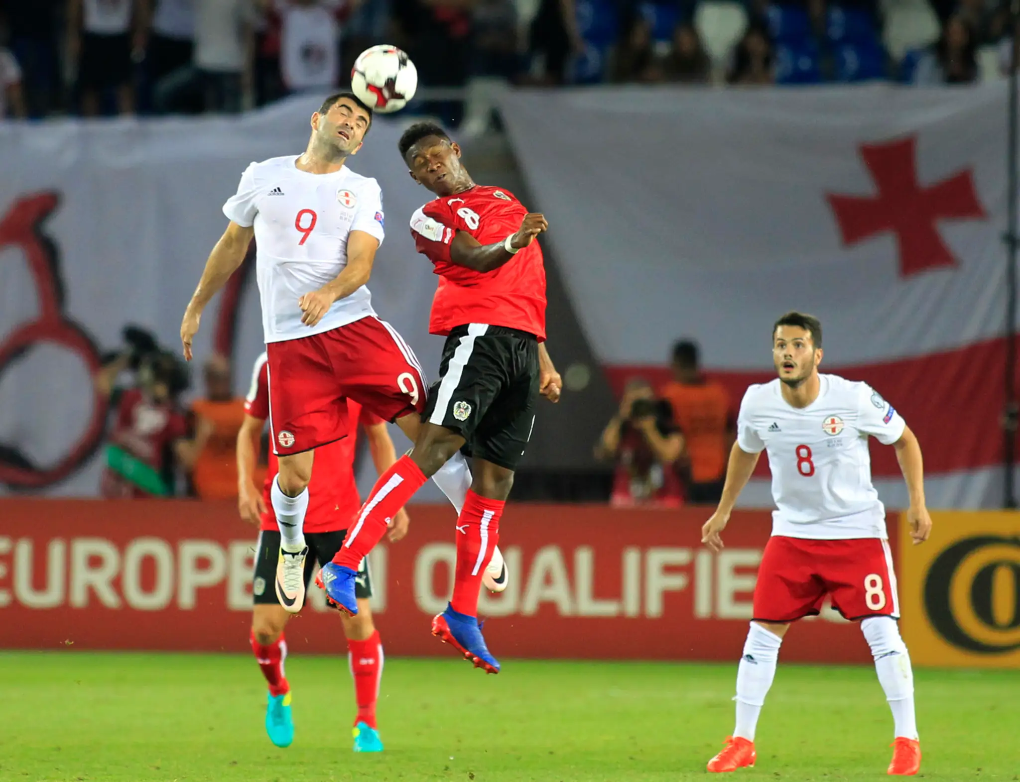 Vladimer Dvališvili z Gruzínska (v bielom) vo vzdušnom súboji proti Rakušanovi Davidovi Alabovi v kvalifikácii MS 2018. 