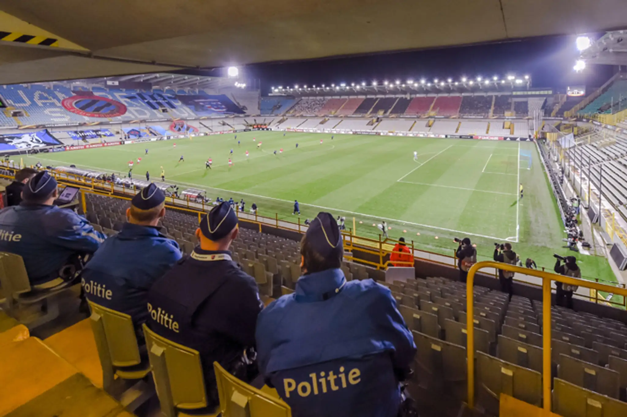Policajti sedia na prázdnom štadióne počas zápasu D-skupiny EL UEFA medzi FC Bruggy a SSC Neapol.