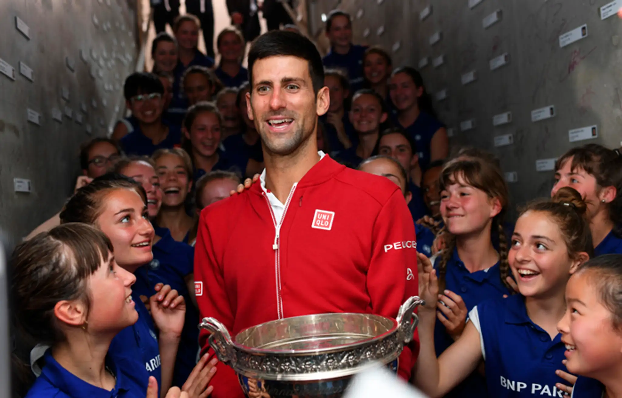 Novak Djokovič sa raduje zberačkami loptičiek po jeho víťazstve na Roland Garros.