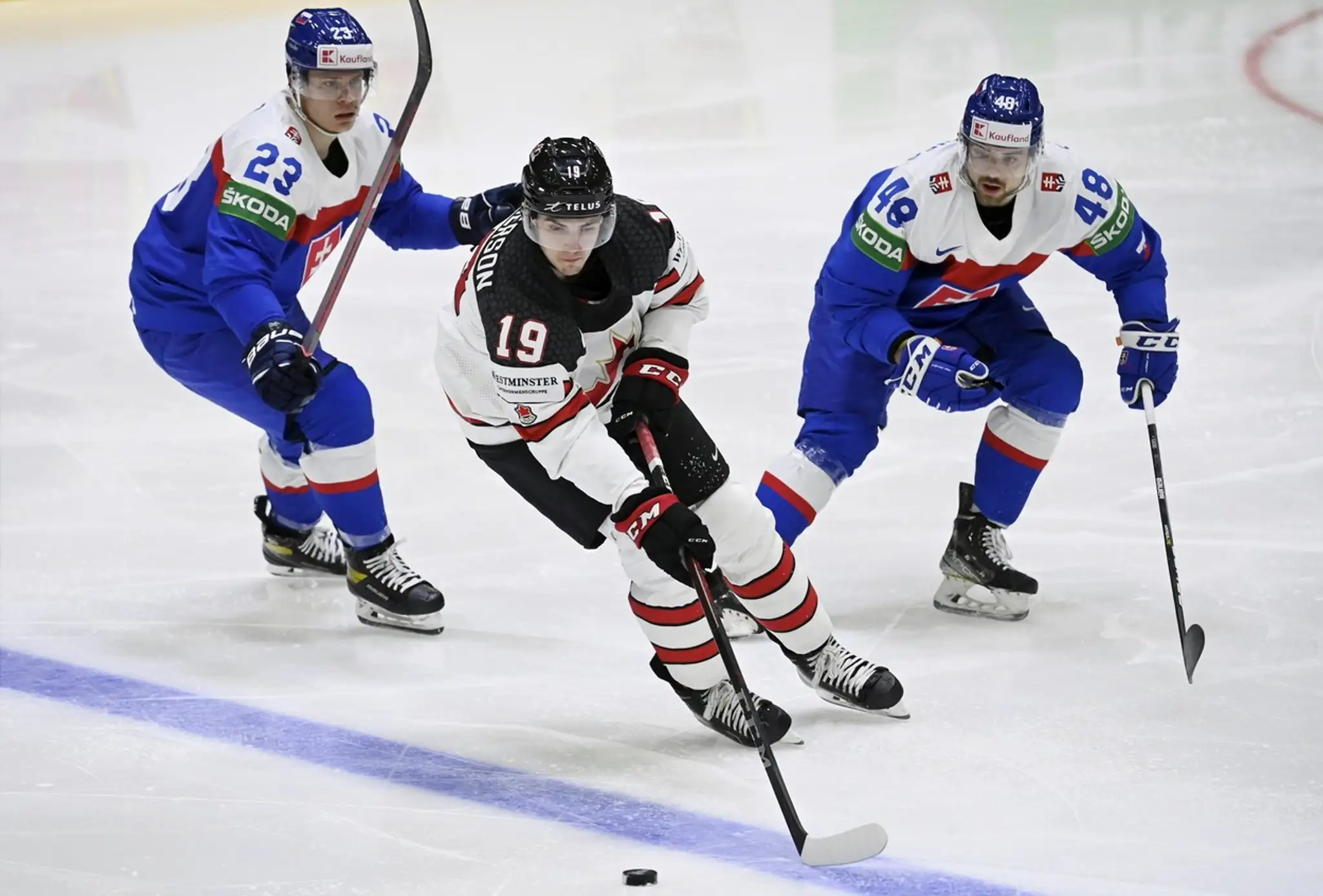 Kanaďan Drake Batherson (v strede) v obkľúčení Slovákov, zľava Adama Lišku a Daniela Gachulinca na MS 2022.