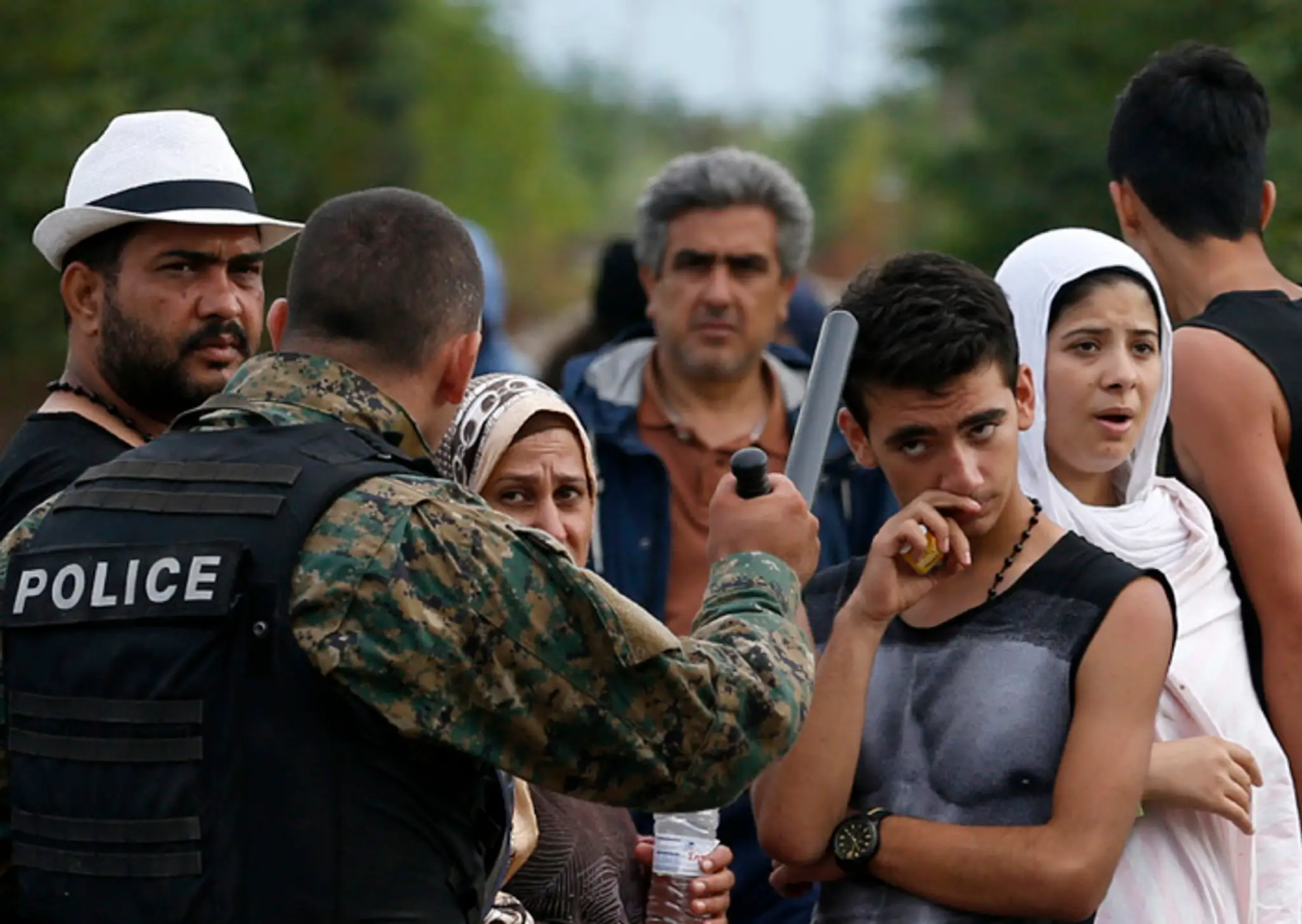 Macedónsky policajt sa rozpráva s migrantami po príchode z Grécka v meste Gevgelija na juhu Macedónska.