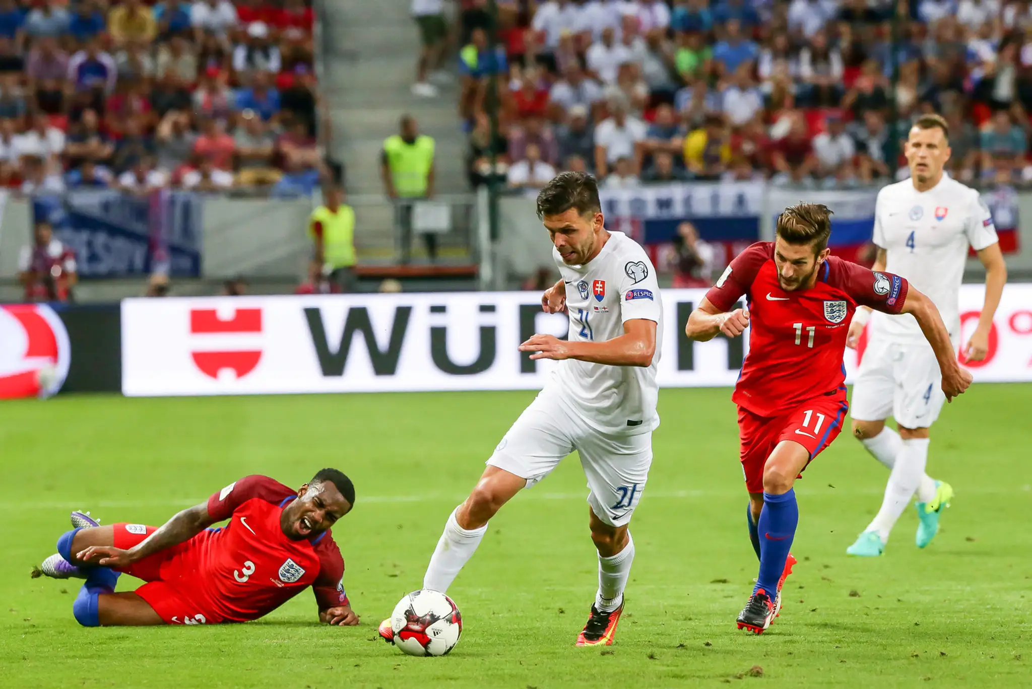 Michal Ďuriš (v bielom) v súboji proti Angličanovi Adamovi Lallanovi v dueli kvalifikácie MS 2018, na zemi sa krčí Danny Rose.