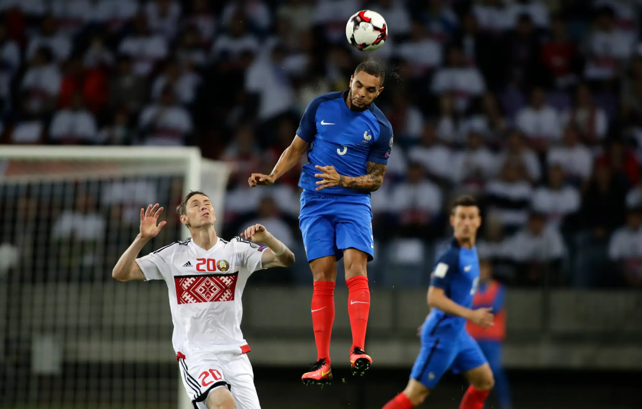 Francúzsky bek Layvin Kurzawa (v modrom) v hlavičkovom súboji s Bielorusom Nikolajom Signevičom v kvalifikácii MS 2018.