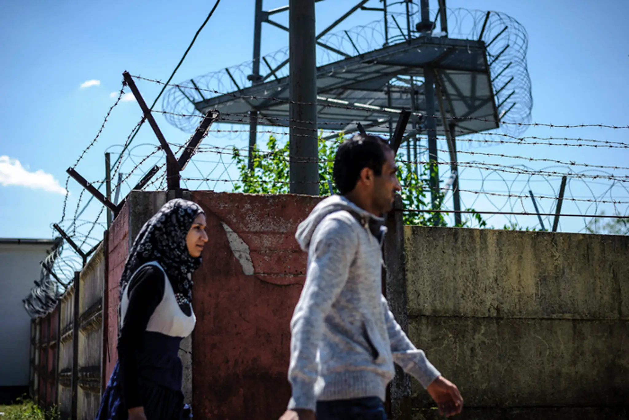 Nelegálni migranti kráčajú okolo plotu utečeneckého tábora v Debrecíne.