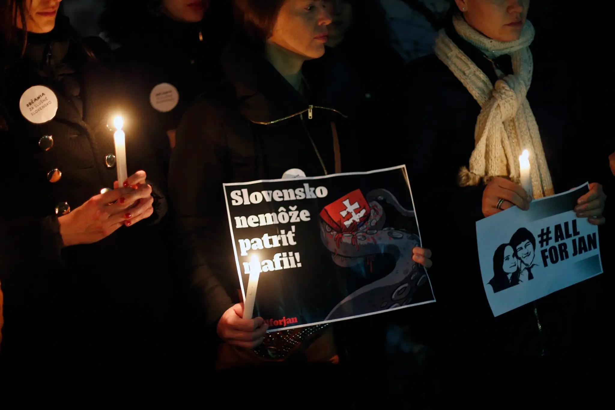 Slováci držia sviečky a transparent s nápisom Slovensko nemôže patriť mafii počas zhromaždenia v Paríži.