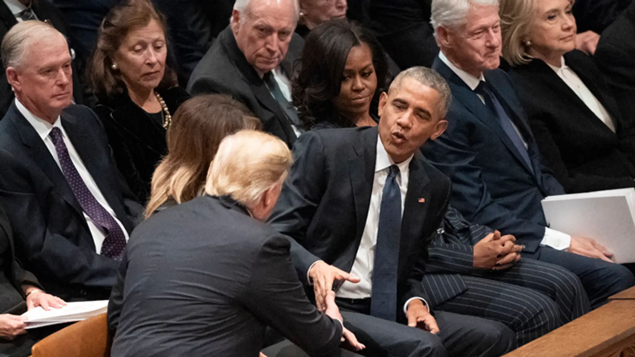 Prezident Donald Trump si podáva ruku s predchodcom Barackom Obamom na pohrebe Georgea Busha.