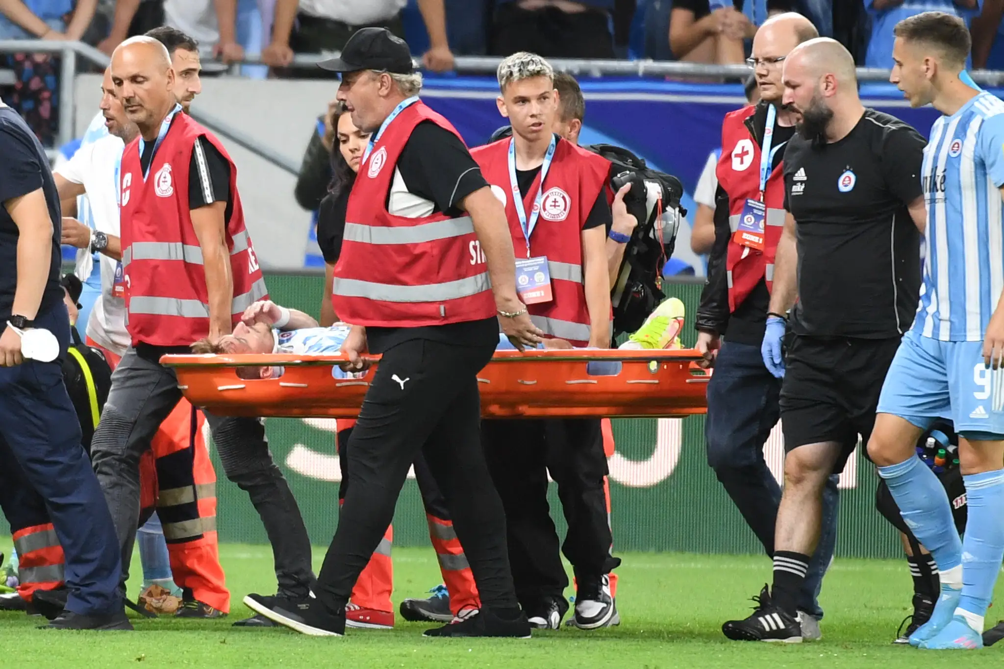 Futbalista Slovana Jurij Medveděv leží na nosidlách počas proti Ferencvárosu.