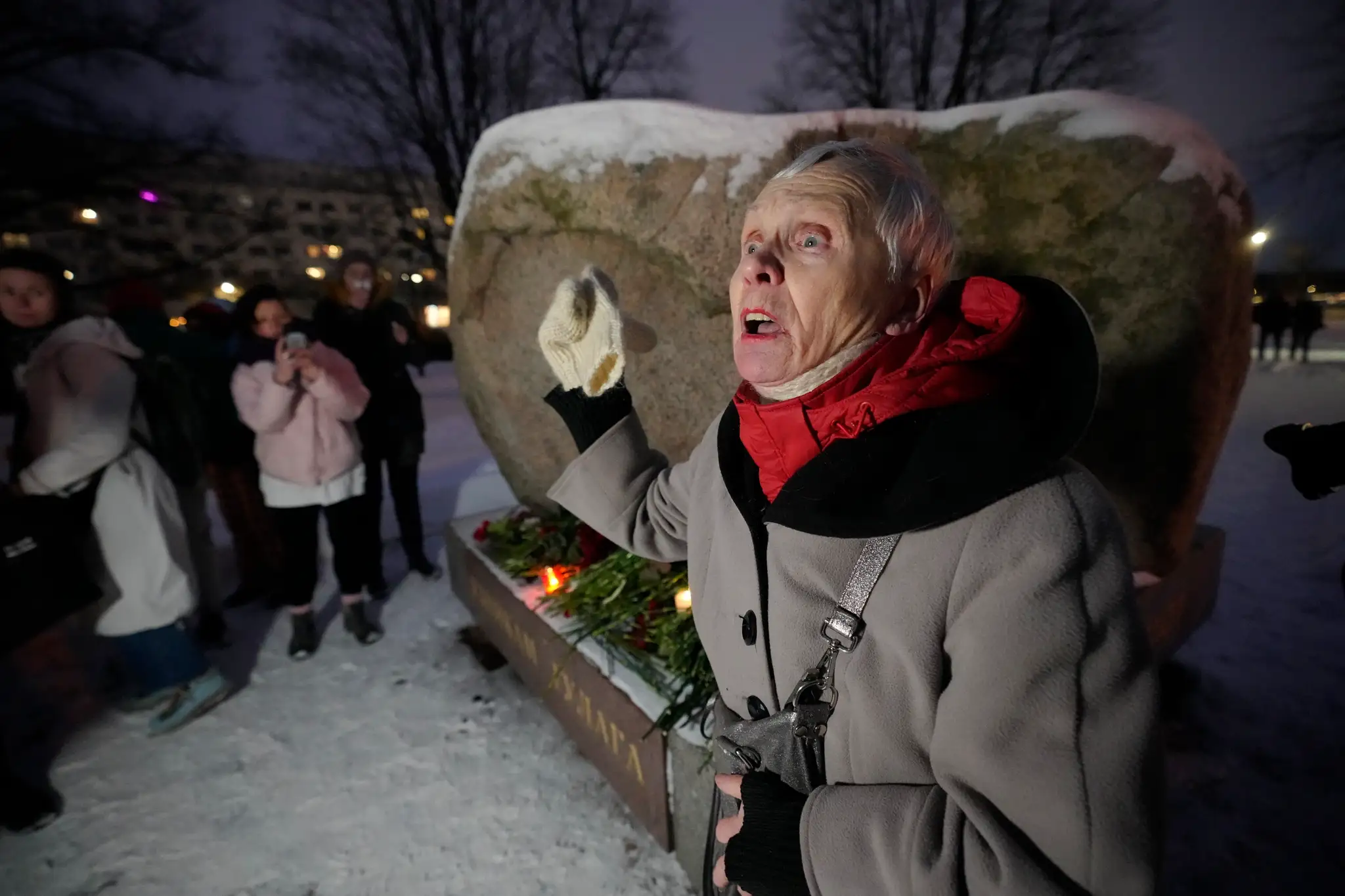 Osemdesiattriročná žena sa prihovára ľuďom, ktorí kladú kvety k pamätníku politických väzňov v Moskve. 