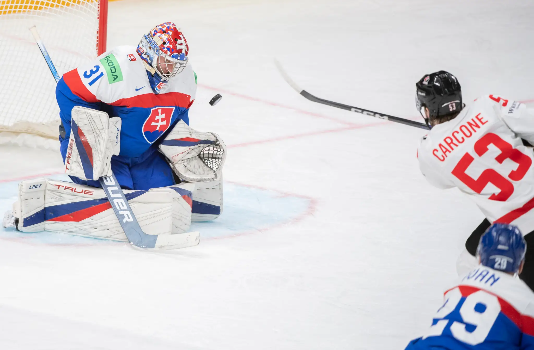 Na snímke vľavo brankár Slovenska Samuel Hlavaj a vpravo útočník Kanady Michael Carcone.
