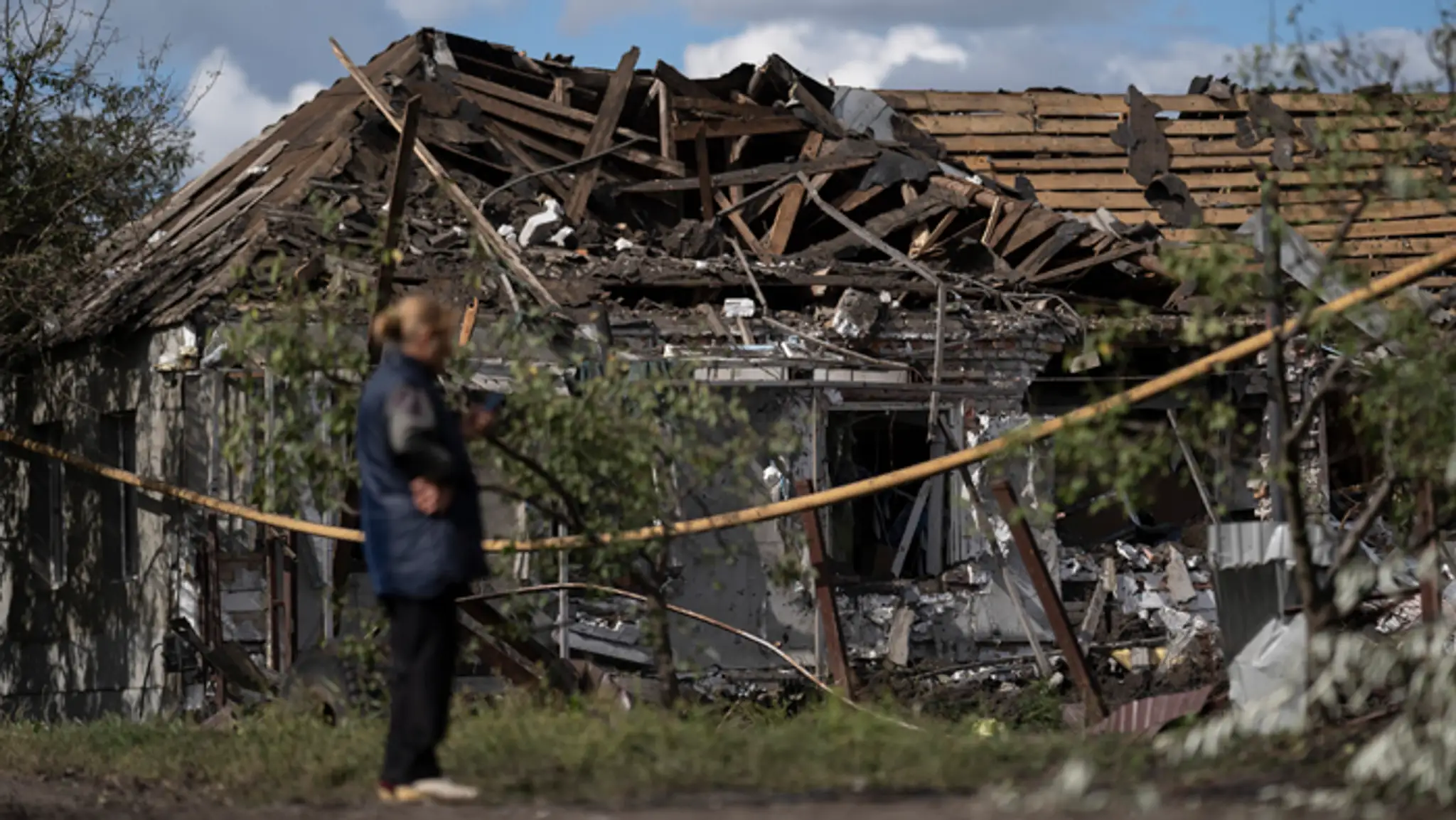Žena stojí pred zničeným domom po ruskom raketovom útoku v meste Sloviansk.