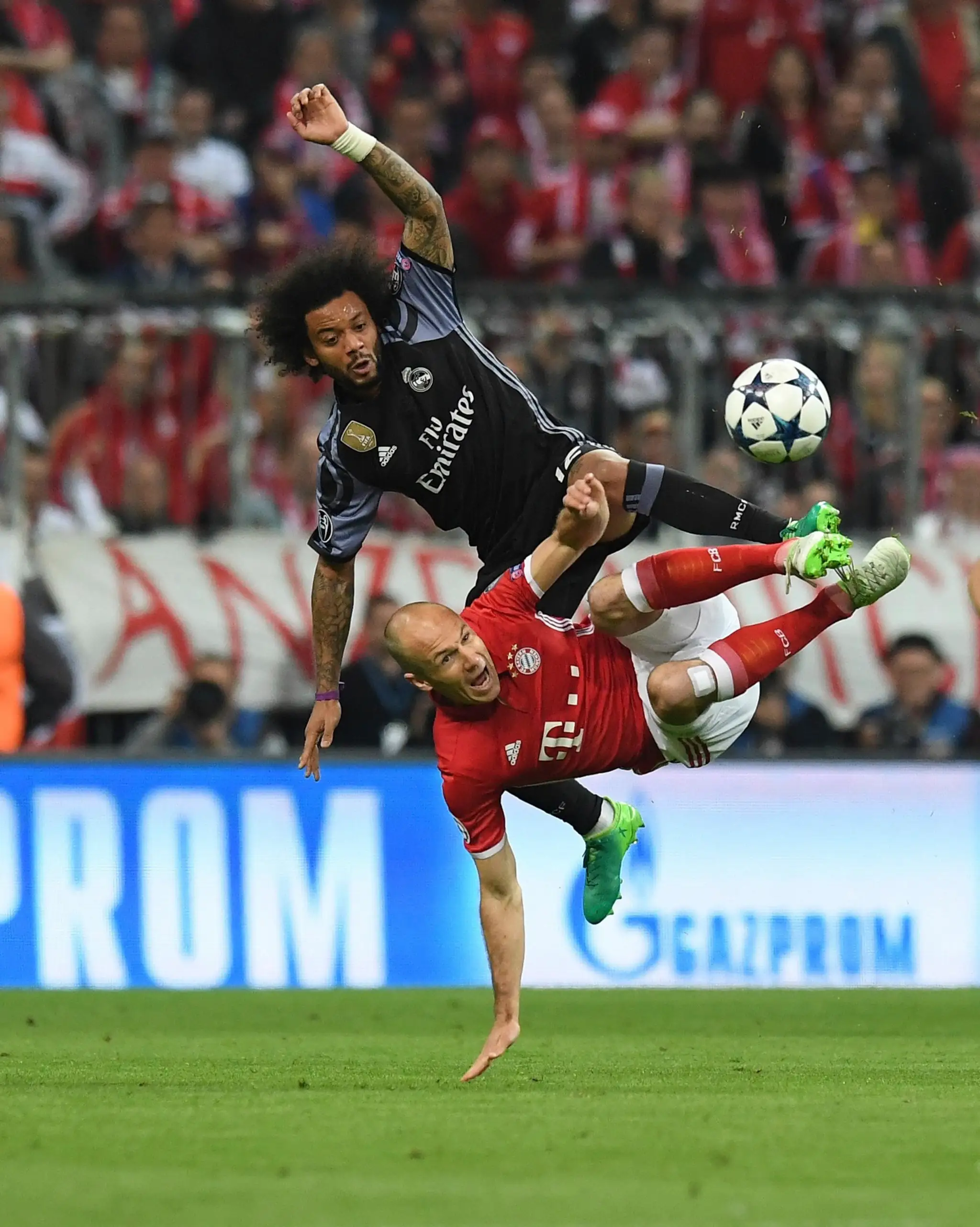 Drsný súboj o loptu vo štvrťfinále LM, hore Marcelo z Realu a pod ním Arjen Robben (Bayern).