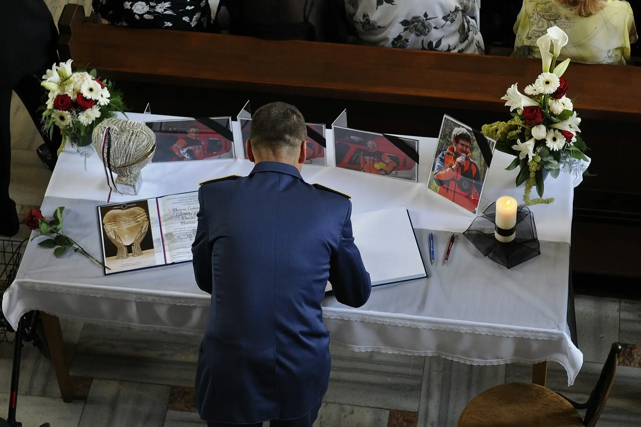 Na snímke muž sa zapisuje do kondolenčnej knihy počas rozlúčky s obeťami havárie vrtuľníka