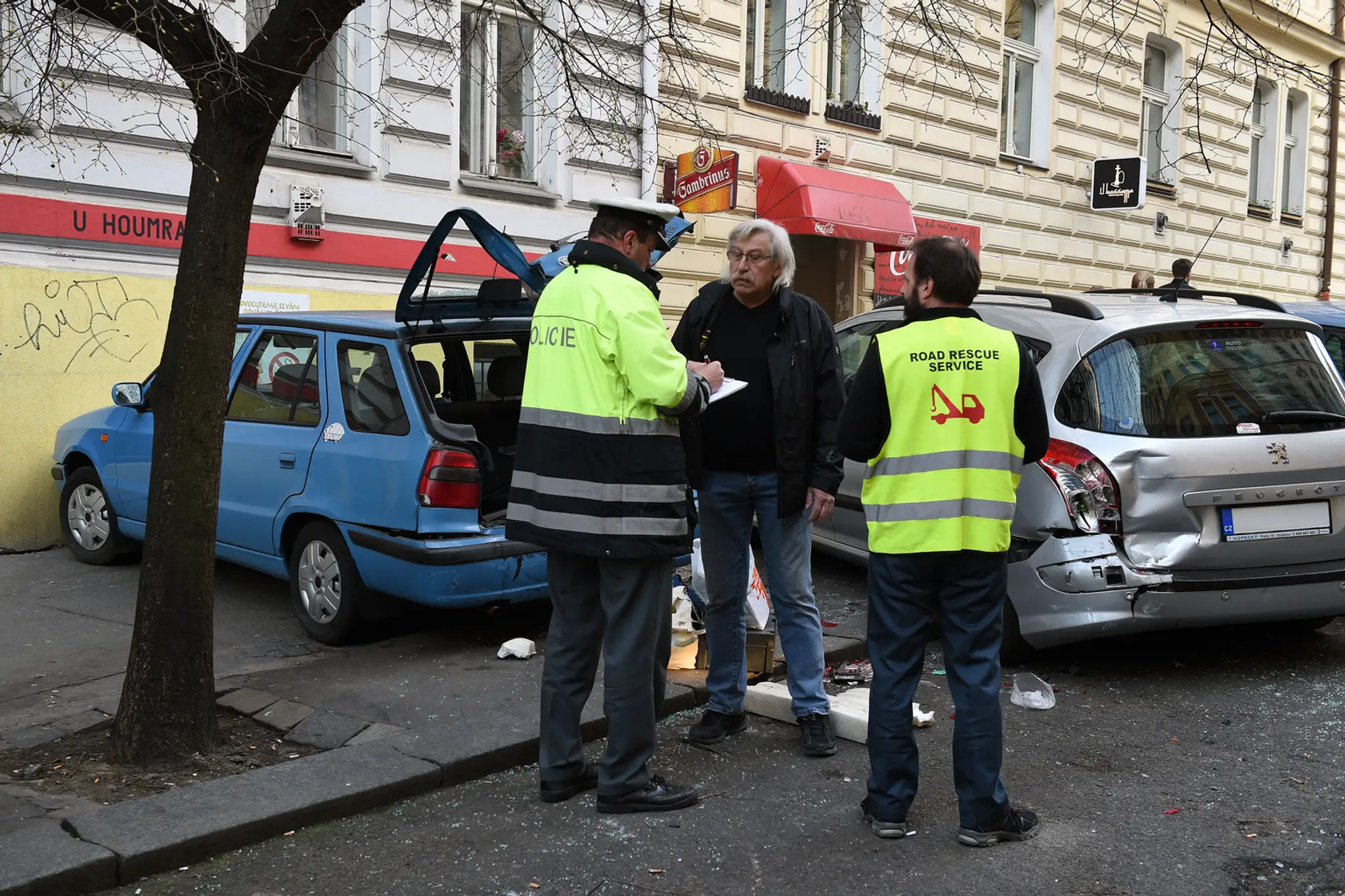 Policajti spisujú škody na aute s jeho majiteľom.