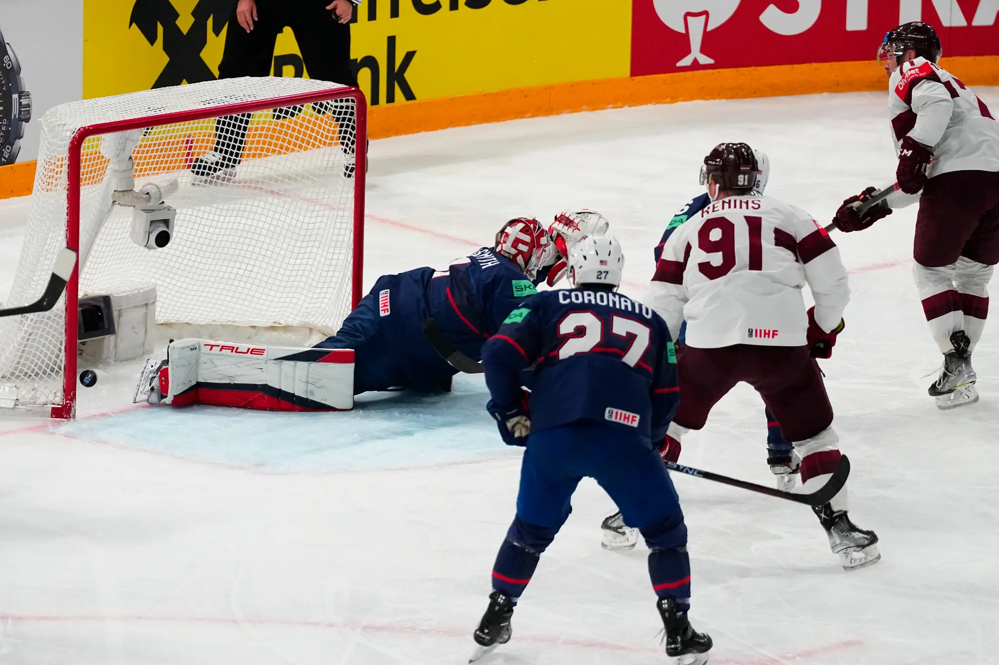  Na snímke vpravo lotyšský útočník Roberts Bukarts strieľa gól, vľavo dole prekonaný brankár USA  Casey DeSmith