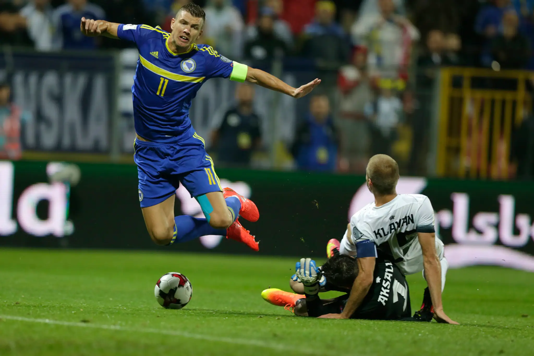 Bombardér Bosny Edin Džeko v súboji s estónskym gólmanom Michelom Aksaluom a bekom Ragnarom Klavanom v kvalifikácii MS 2018.