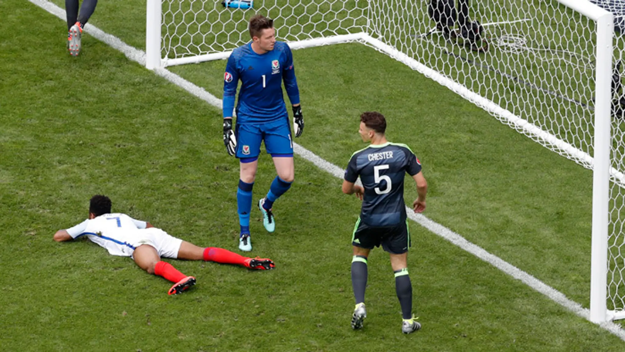 Anglický futbalista Raheem Sterling leží na trávniku po nepremenení gólovu proti Walesu.