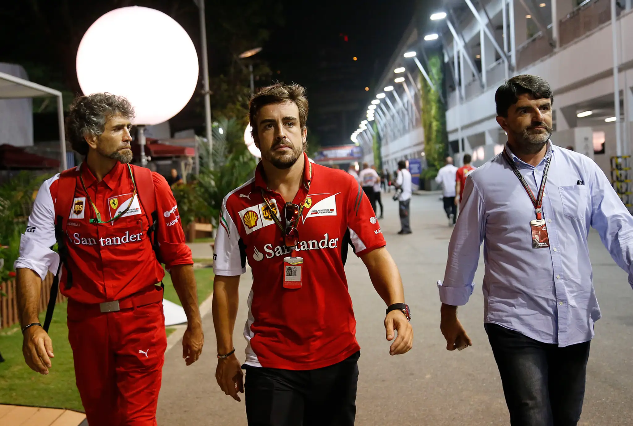 Španielsky pilot formuly 1 Fernando Alonso (uprostred) z tímu Ferrari v sprievode tímových kolegov v Singapure.