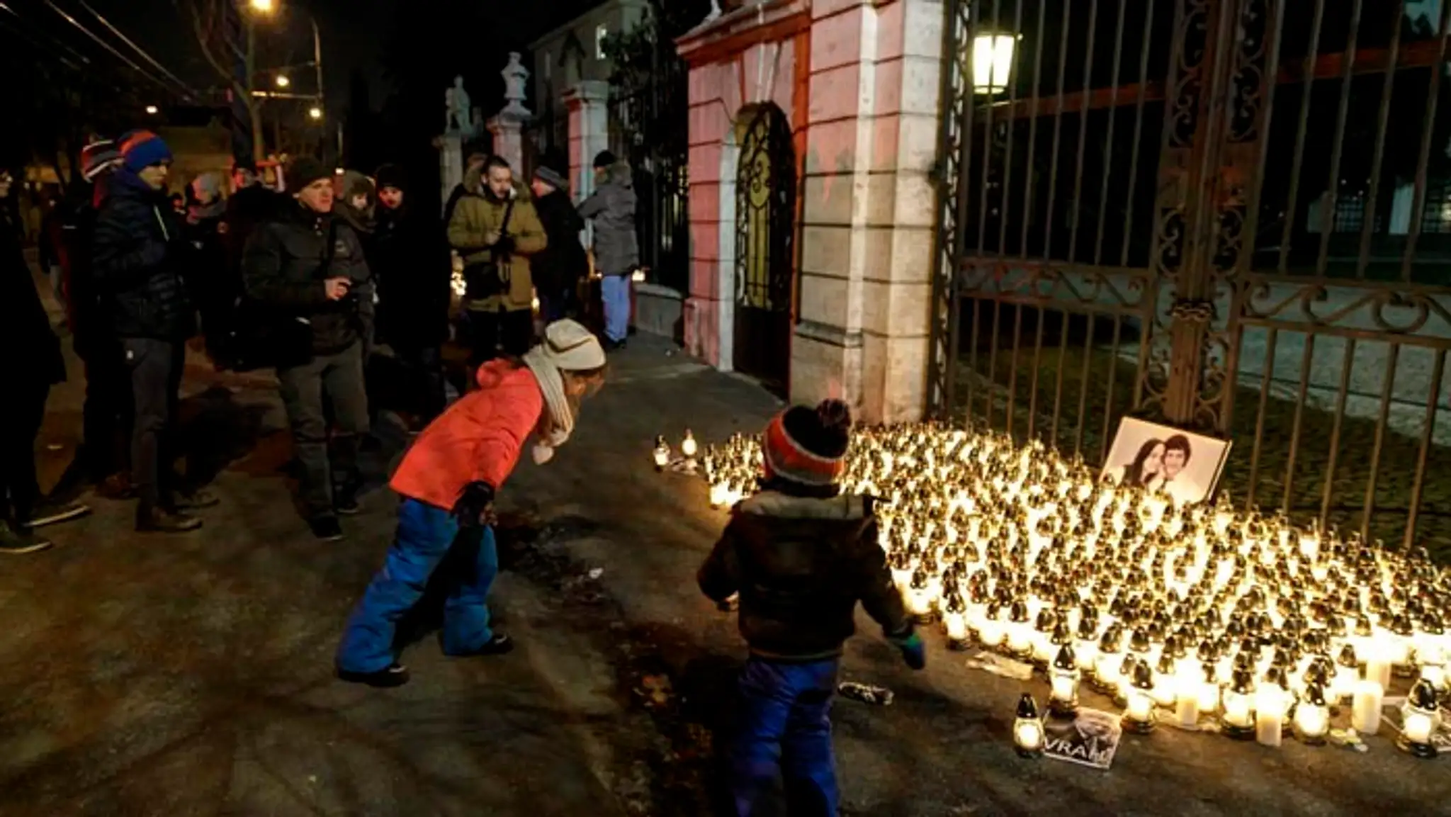 Účastníci tichého spomienkového pochodu zapálili na pamiatku zavraždeného novinára a jeho snúbenice sviečky. 