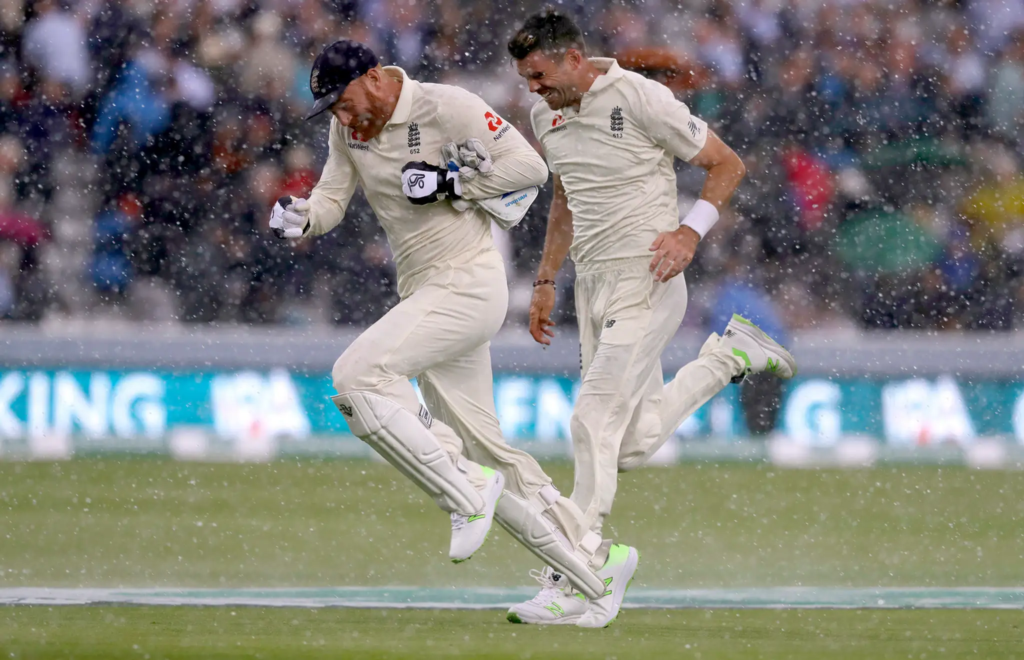 Anglickí reprezentanti v krikete Jonny Bairstow a James Anderson utekajú pred dažďom v dueli proti Indii.