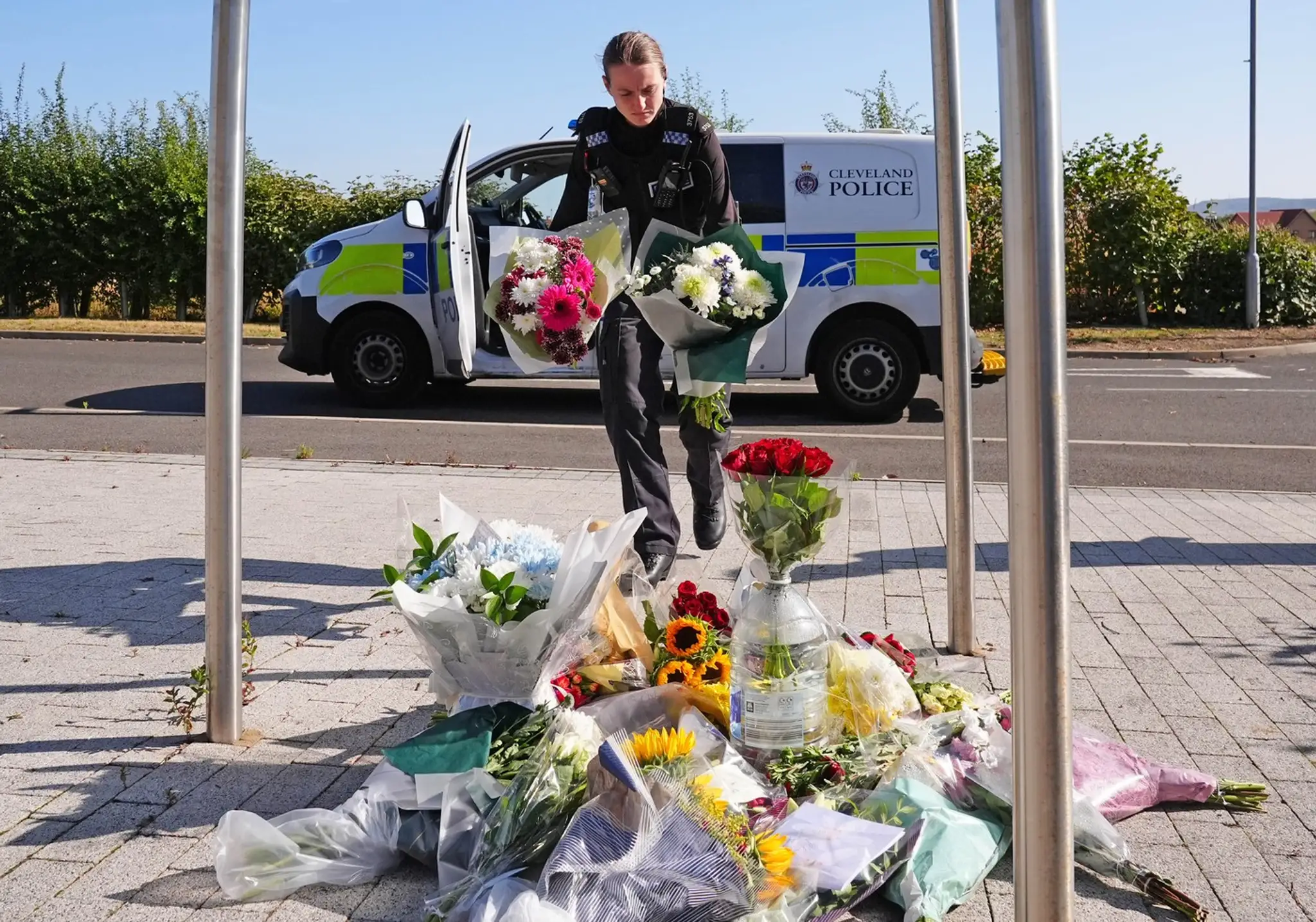 Policajtka kladie kvety v Pamätnej záhrade v Middlesbroughu po smrti policajtov Matthewa Bladesa a Toma Clougha pri výkone služby.