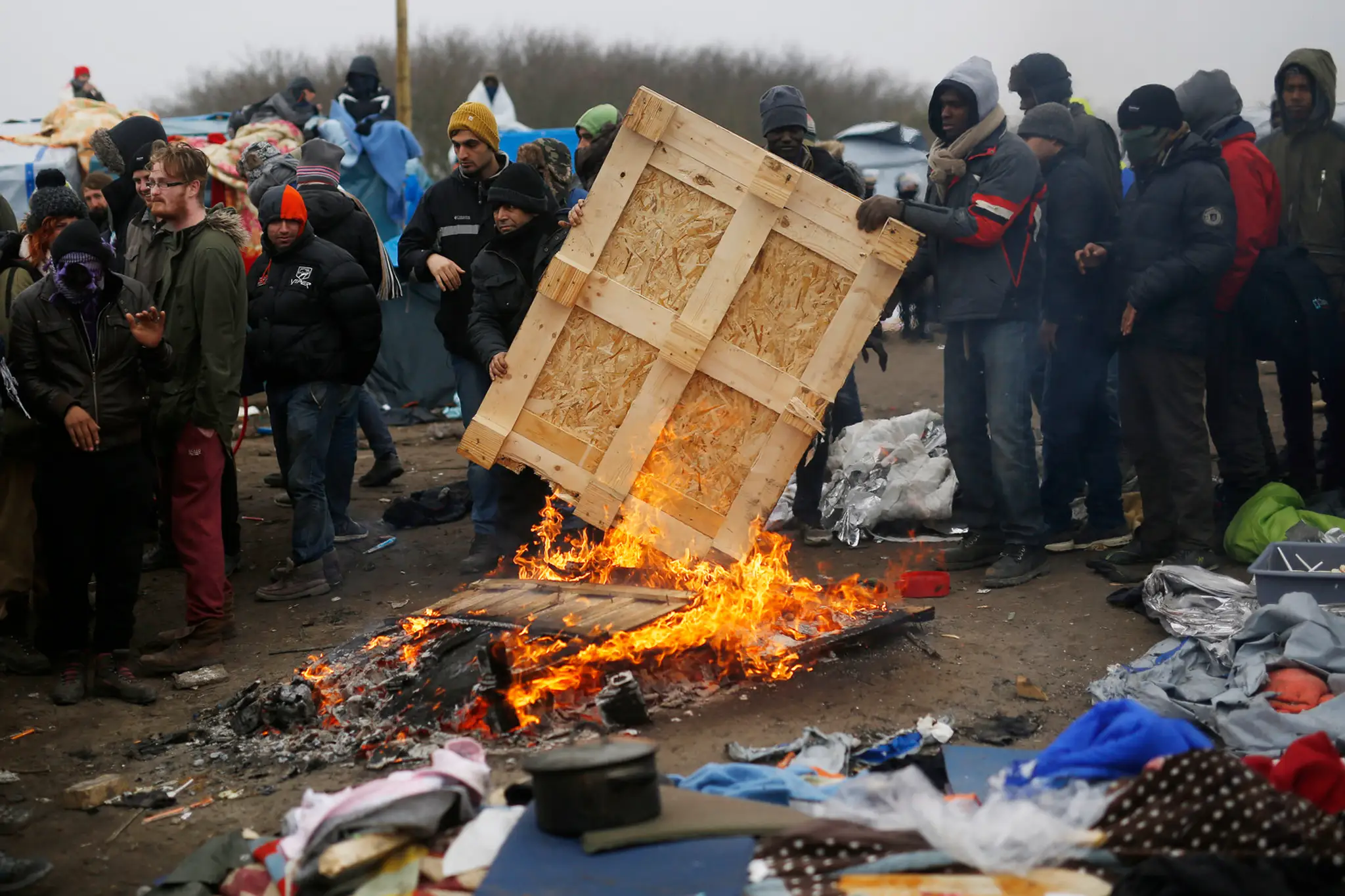 Migranti v tábore pri Calais protestujú na strechách búd.