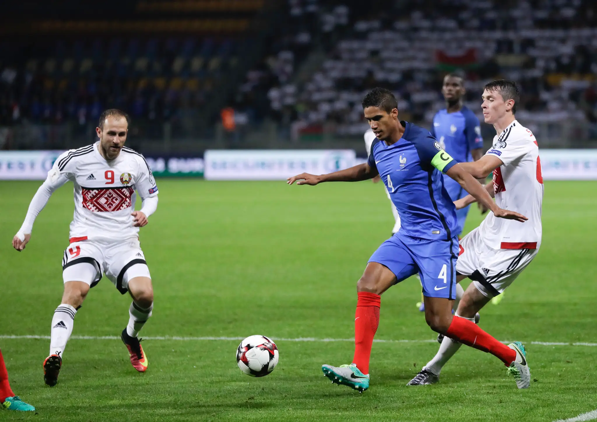 Kapitán Francúzska Raphael Varane (v modrom) bránený Bielorusmi Igorom Staševičom (vľavo) a Nikolajom Signevičom v kvalifikácii 