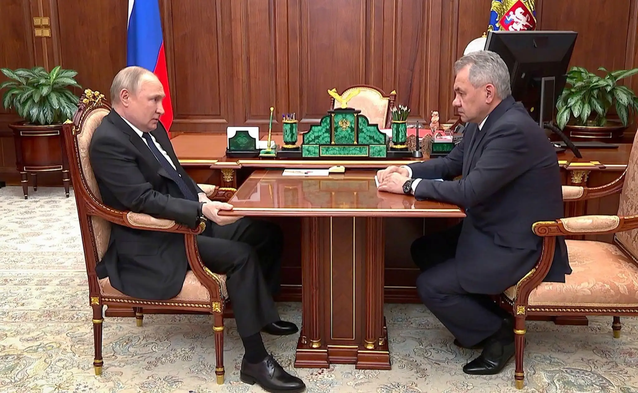 Vladimir Putin sa pravou rukou pridrdržiava stola počas stretnutia s ministrom obrany Sergejom Šojguom.