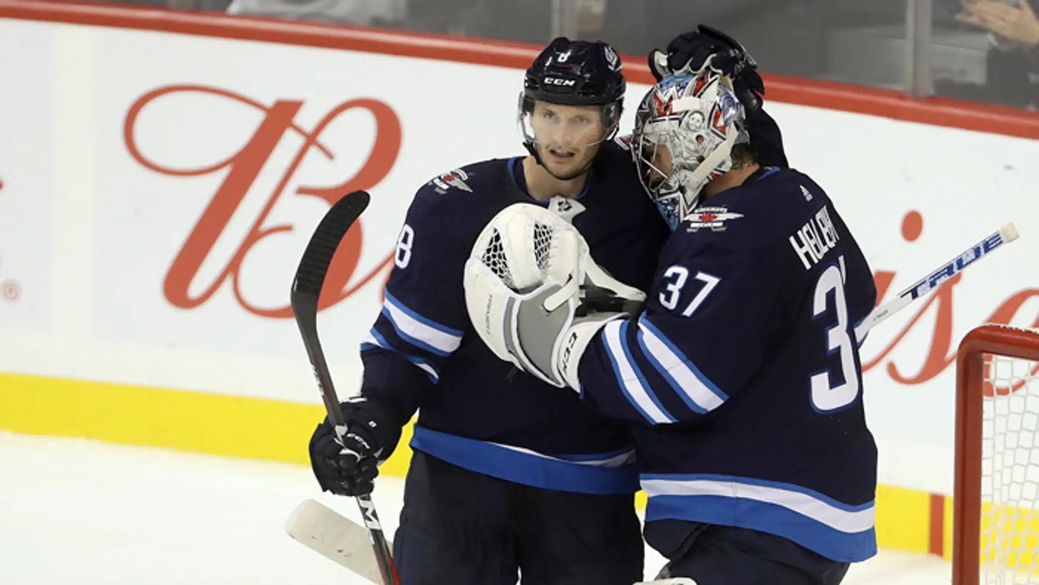 Jacob Trouba z Winnipegu Jets blahoželá brankárovi Cannorovi Hellebuyckovi po víťazstve nad Los Angeles Kings.