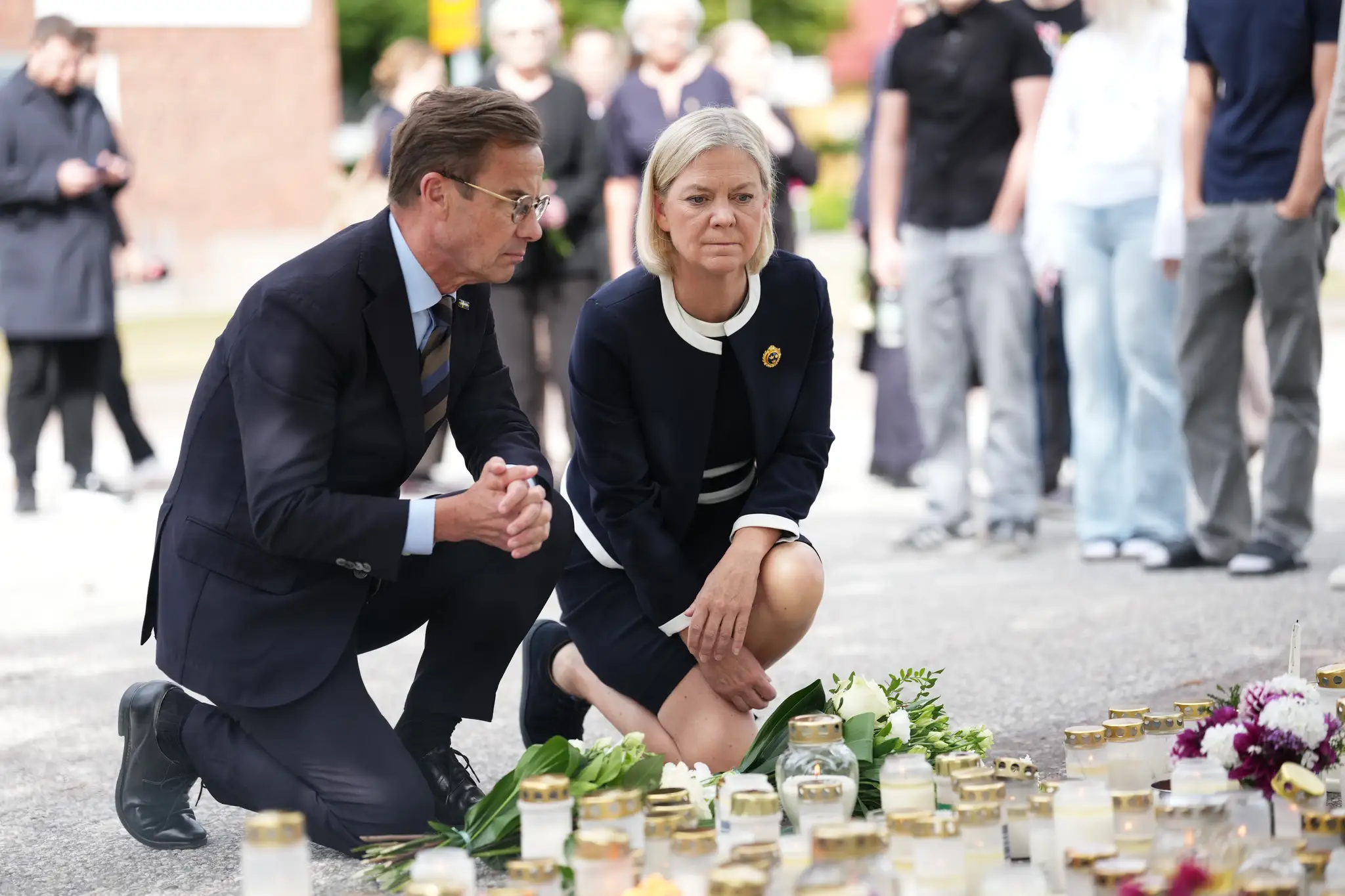 Na snímke švédsky premiér Ulf Kristersson (vľavo) a líderka Sociálnodemokratickej strany Magdalena Anderssonová kladú kvety k provizórnemu pamätníku pred strednou školou Brinell deň po útoku.