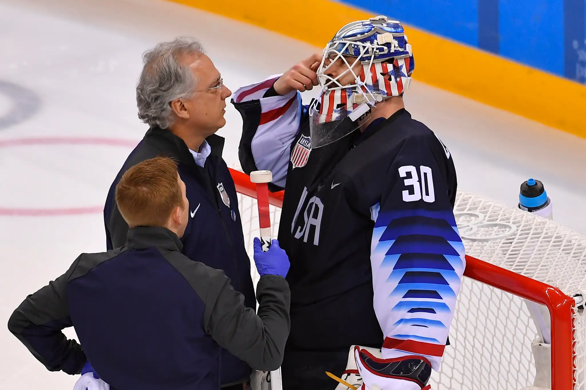 Vpravo brankár USA Ryan Zapolski diskutuje po faule a páde svoj stav s lekármi v osemfinále ZOH 2018 proti Slovensku.