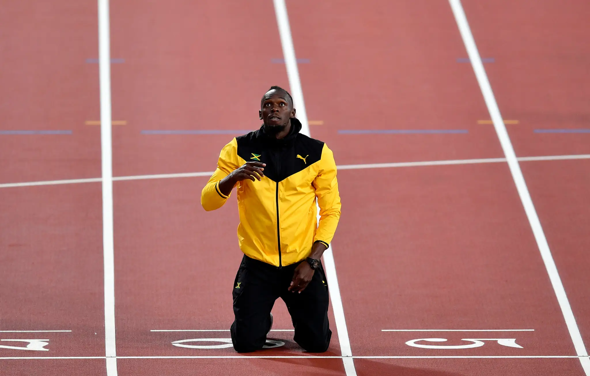 Jamajský šprintér Usain Bolt kľačí na kolenách na cieľovej čiare  jeho symbolického posledného čestného okruhu na záver MS.