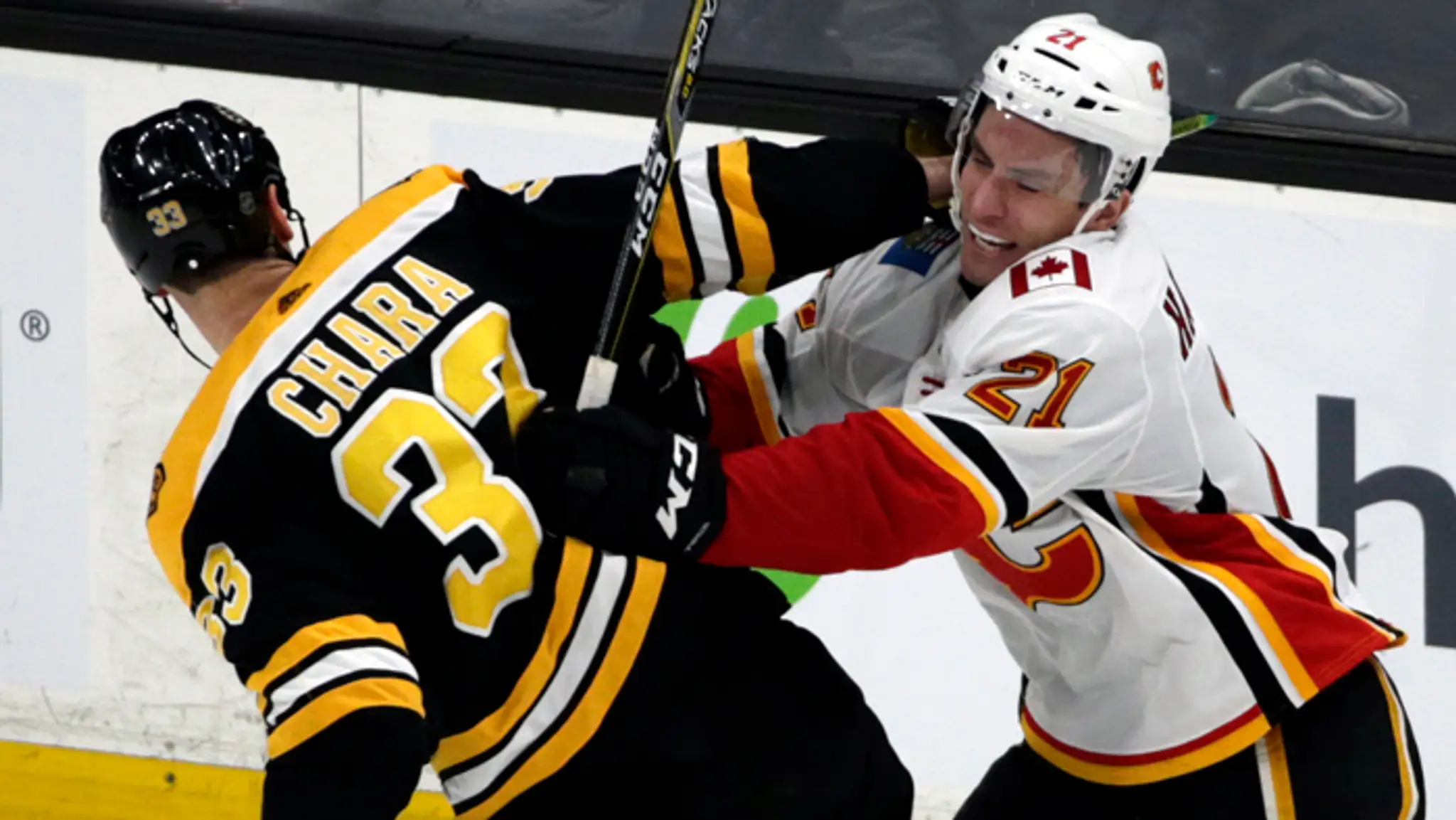 Jaroslav Halák z Bostonu chytá puk pred Michaelom Frolíkom z Calgary.