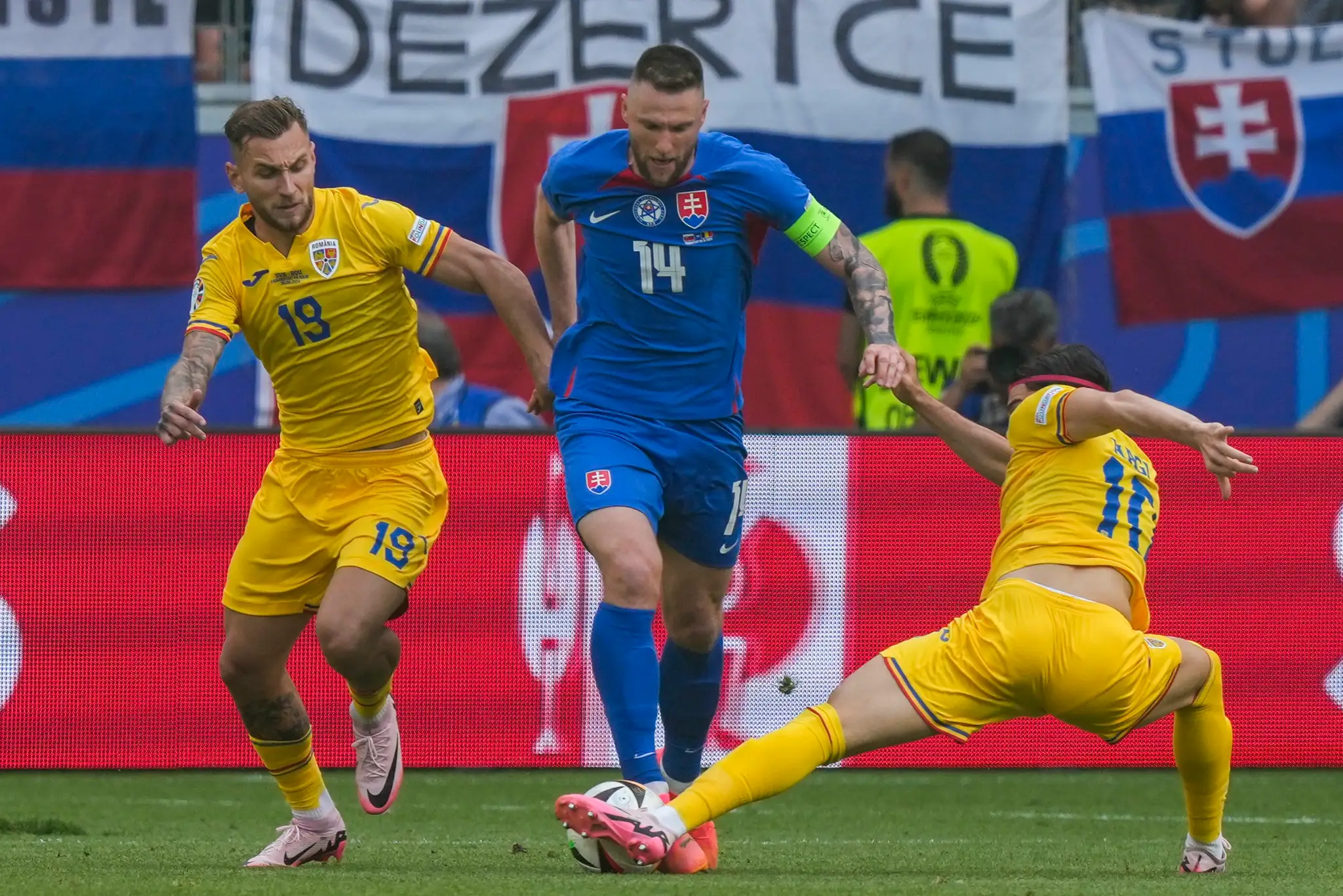 Rumuni zľava Ianis Hag a Denis Dragus obklopili Milana Škriniara v zápase na ME 2024.