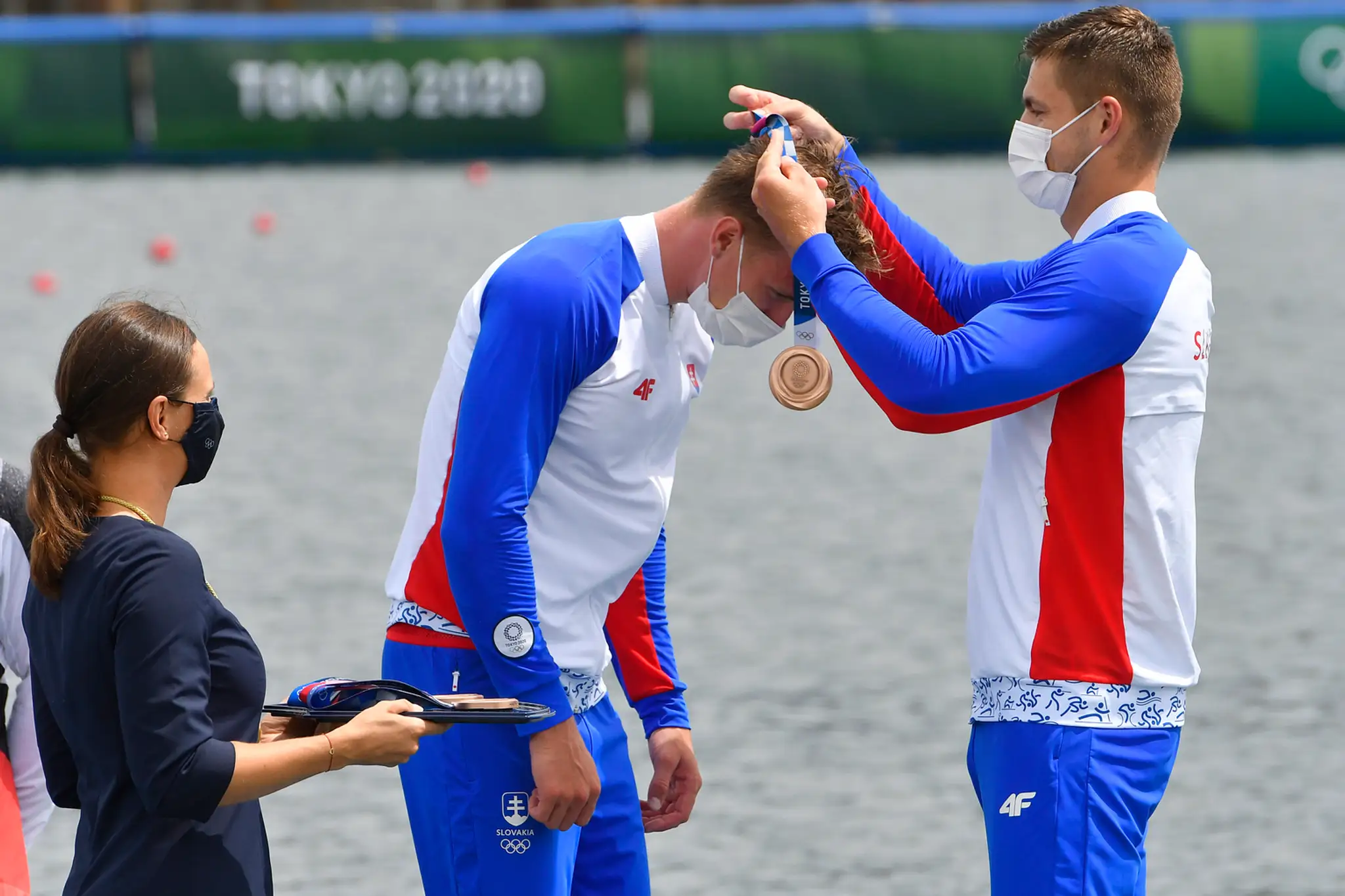 Denis Myšák dekoruje Samuela Baláža bronzovou medailou, ktorú im priniesla Danka Barteková.
