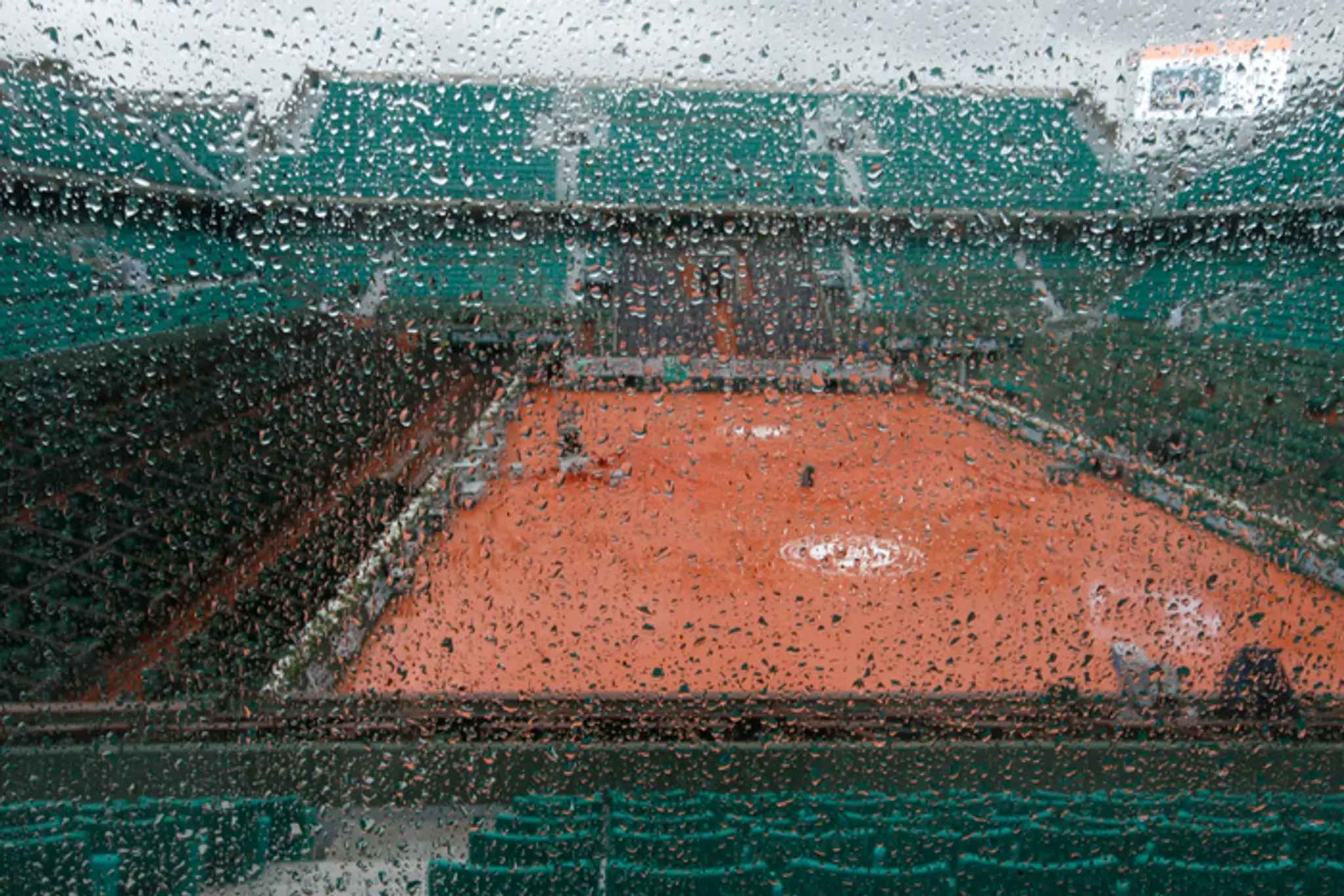 Centrálny kurt vidieť cez sklo počas dažďa pred začiatkom zápasov 1. kola na grandslamovom turnaji Roland Garros. 