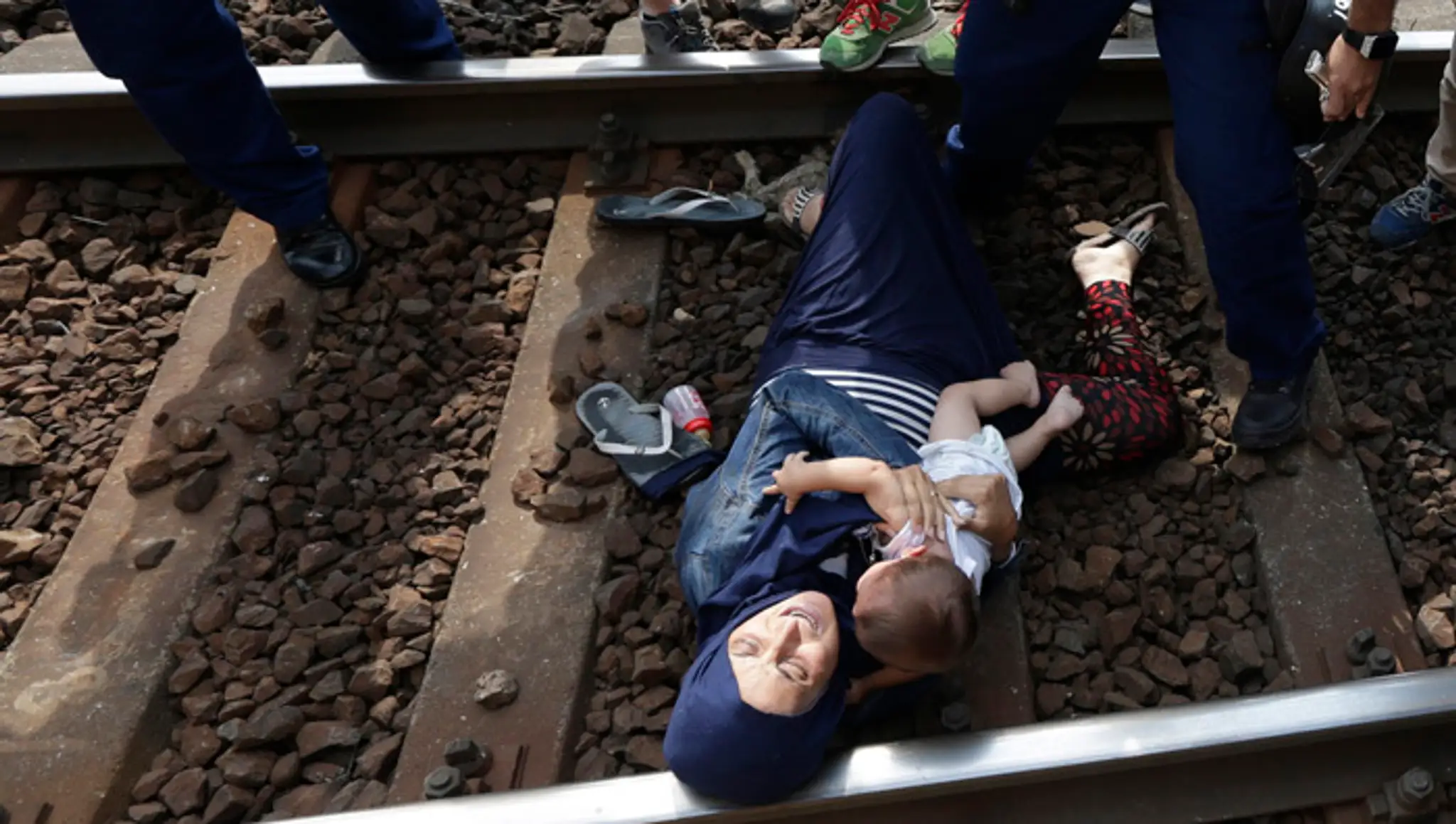 Migrantku, ktorá leží v náručí s dieťaťom na koľajniciach, zatýkajú policajti v maďarskom meste Bicske.