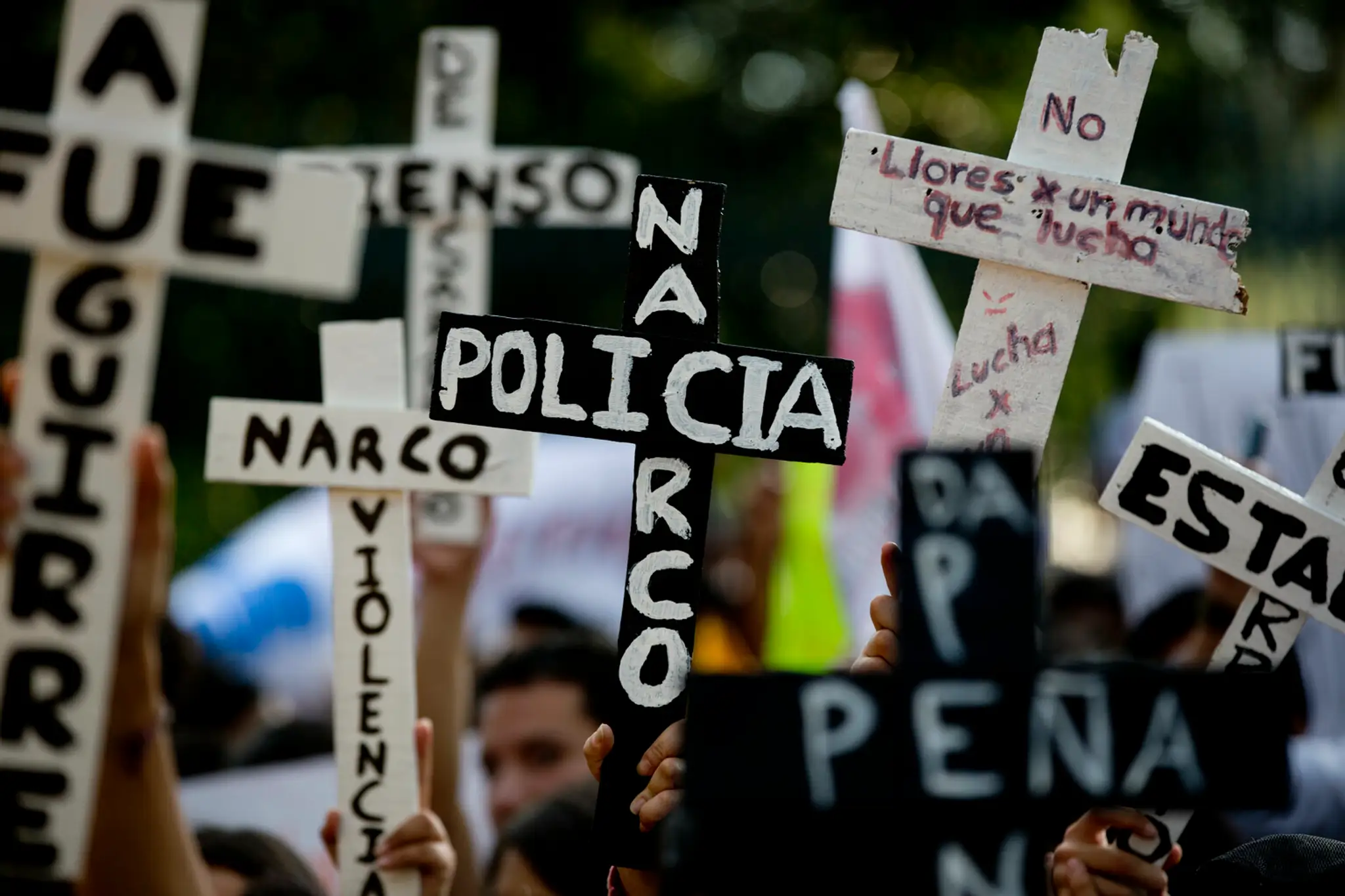 Demonštranti v uliciach Mexica City s nápismi "Narco-polícia" na krížoch.