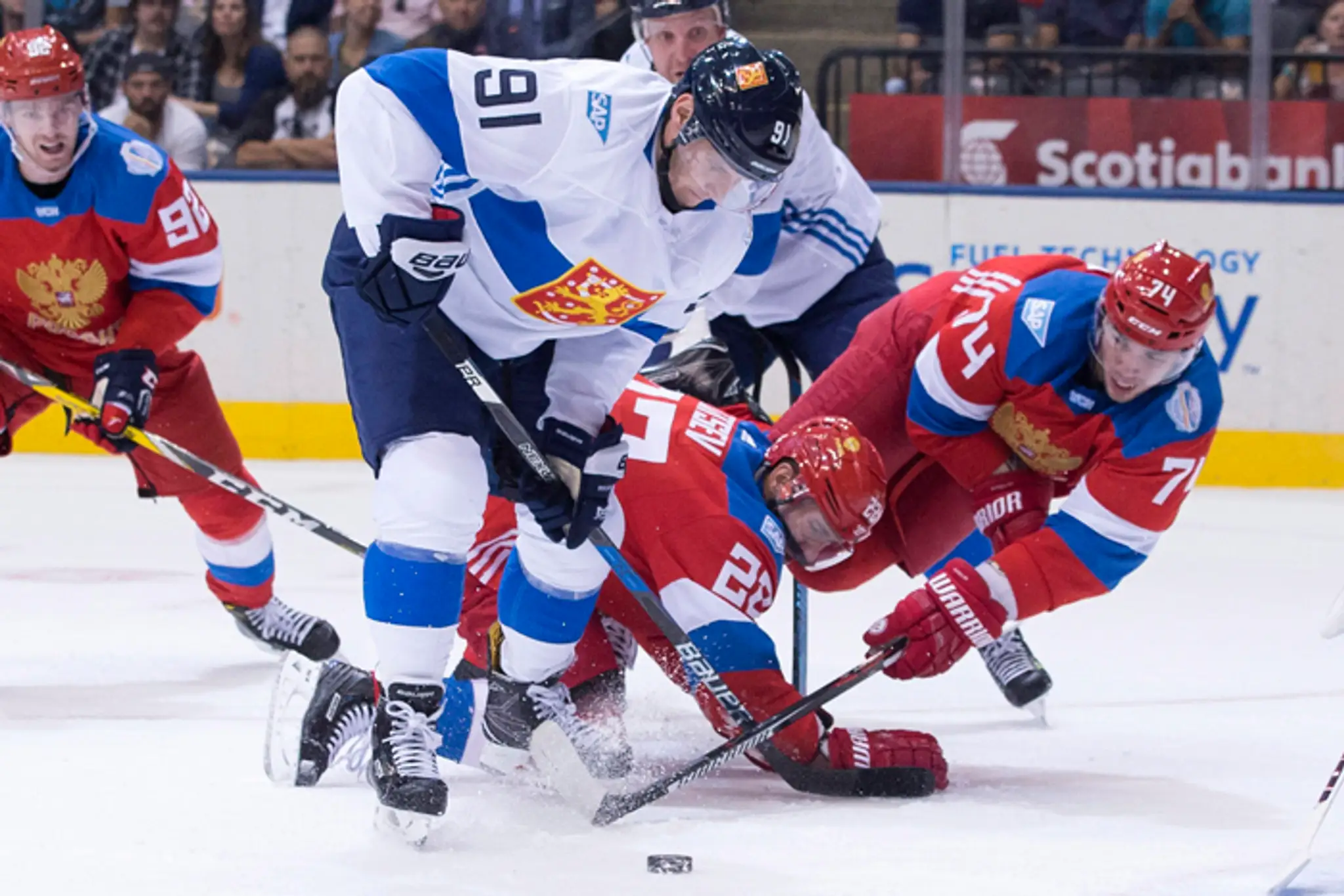 Aleksander Barkov (Fínsko) v boji o puk s Nikitom Zajcevov a Alexejom Jemelinom (obaja Rusko) na SP.