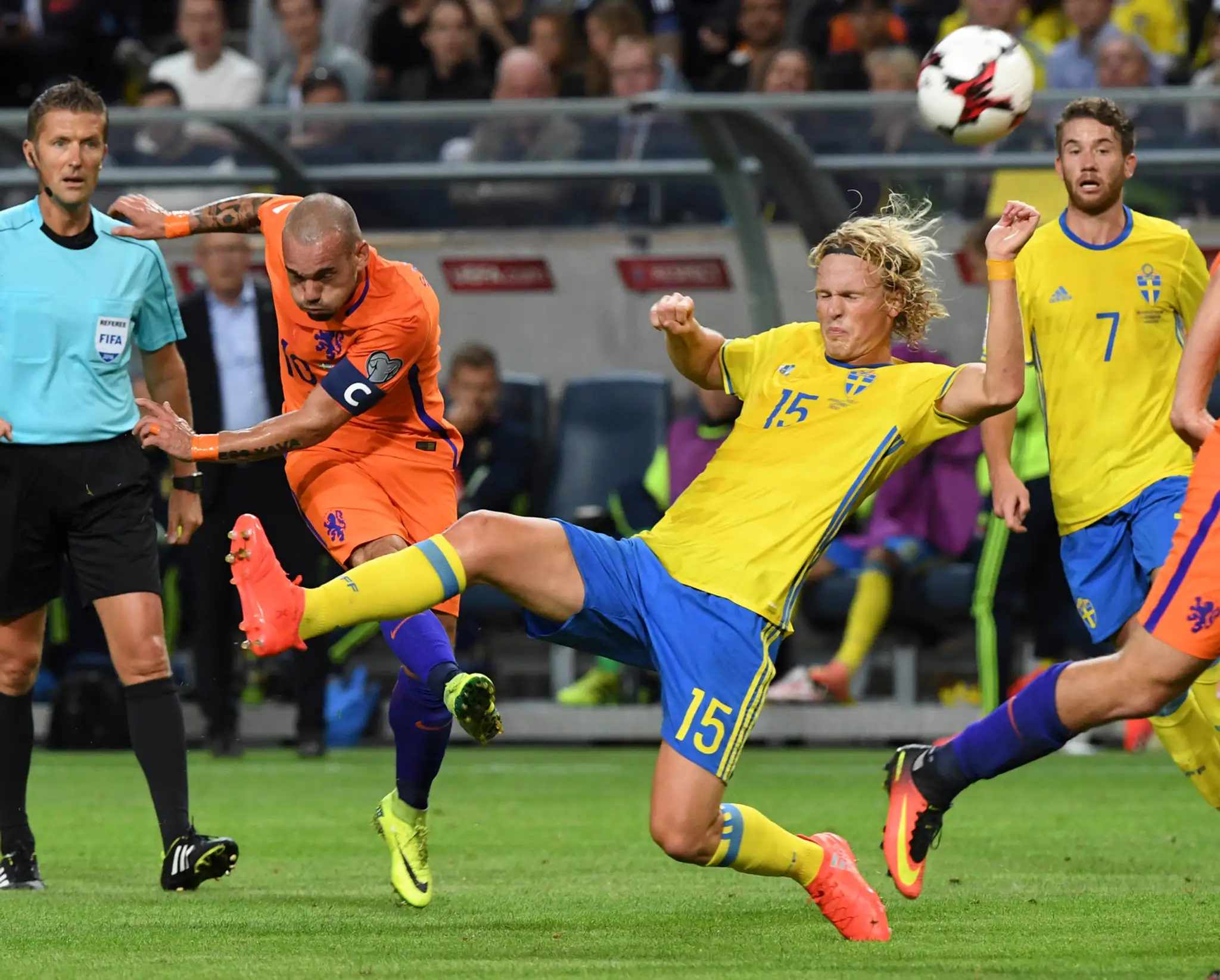 Švéd Oscar Hiljemark (v žltom) bojuje o loptu s holandskou ikonou Wesleym Sneijderom v kvalifikácii MS 2018.