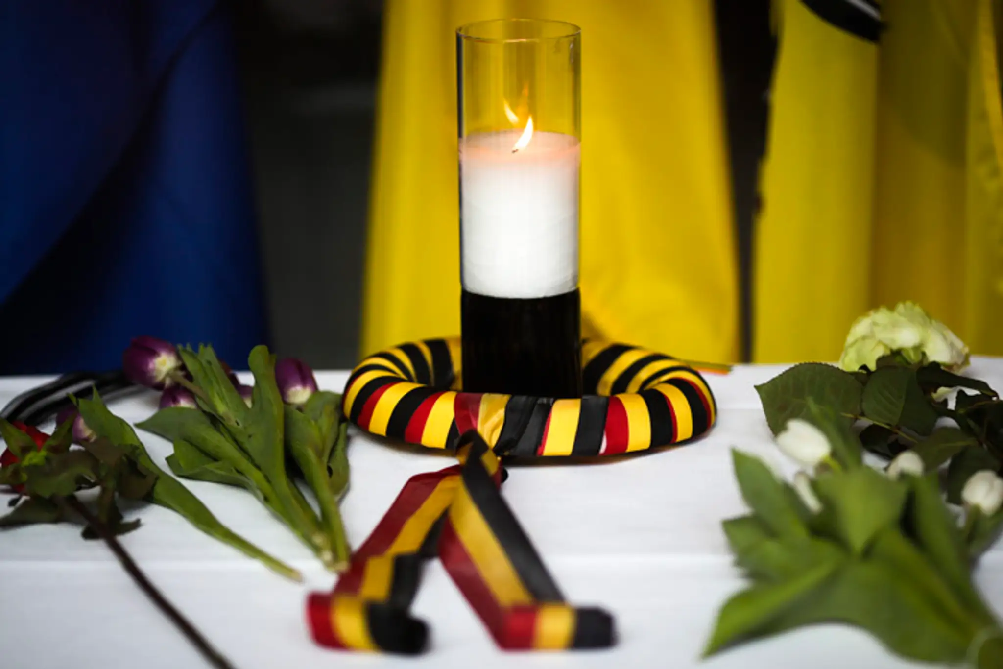 Zapálená sviečka v malom venčeku s belgickou trikolórou a položené kvety na stole vo vnútri belgického veľvyslanectva v Berlíne.