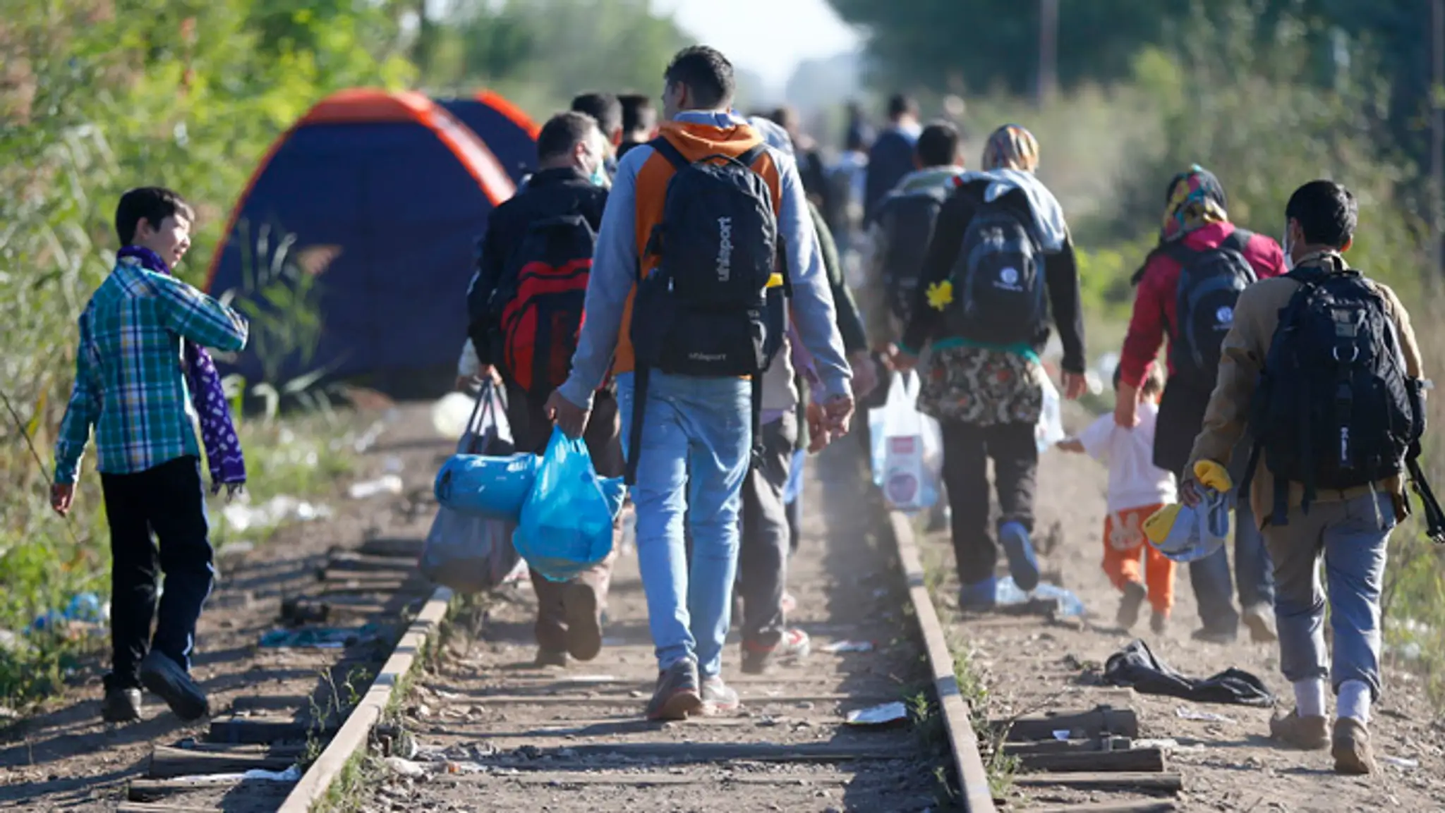 Migranti, ktorí opustili záchytný tábor pre utečencov, kráčajú pešo popri železničnej trati pri obci Röszke na juhu Maďarska,